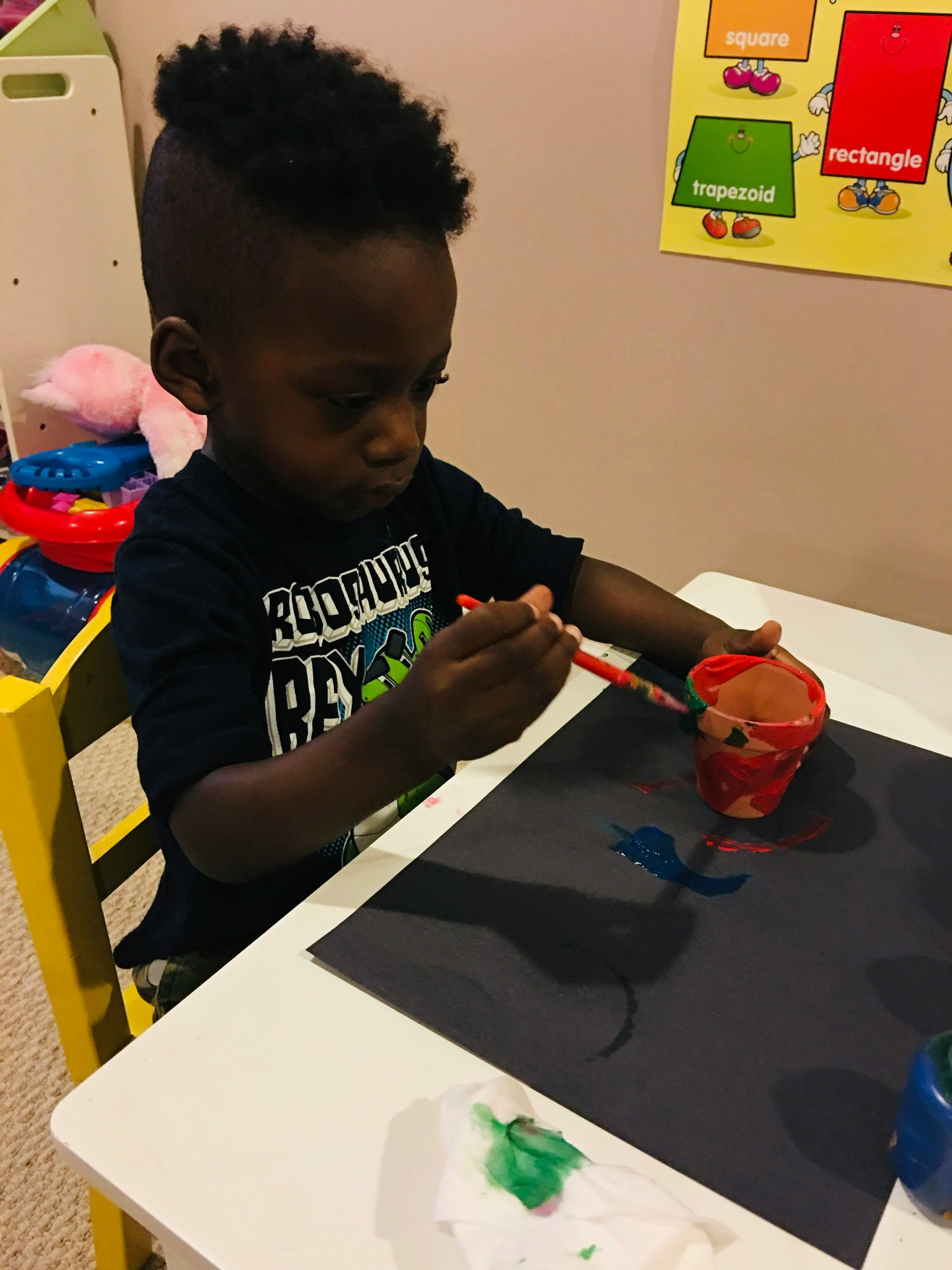 Child painting on black paper at a table