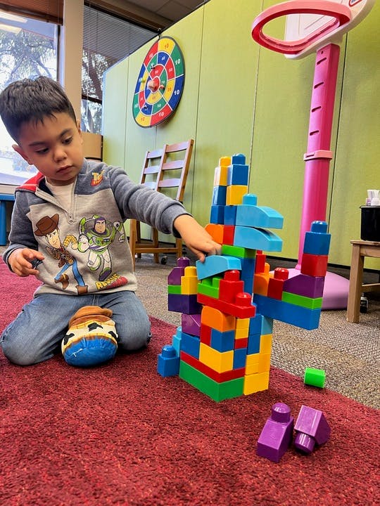 Child playing with colorful building blocks on a red carpet