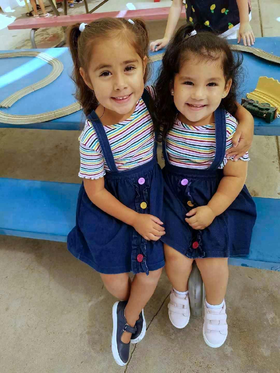 Two children sitting together, one with an arm around the other