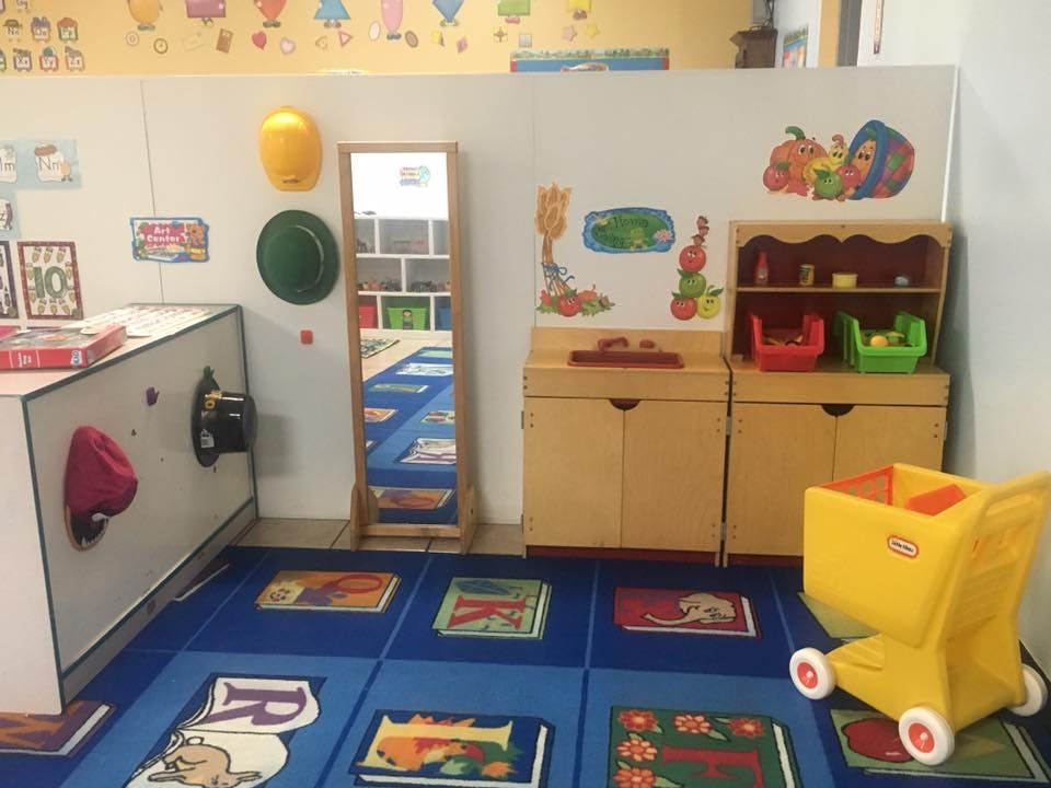 Playroom with blue rug, wooden furniture, and yellow toy shopping cart