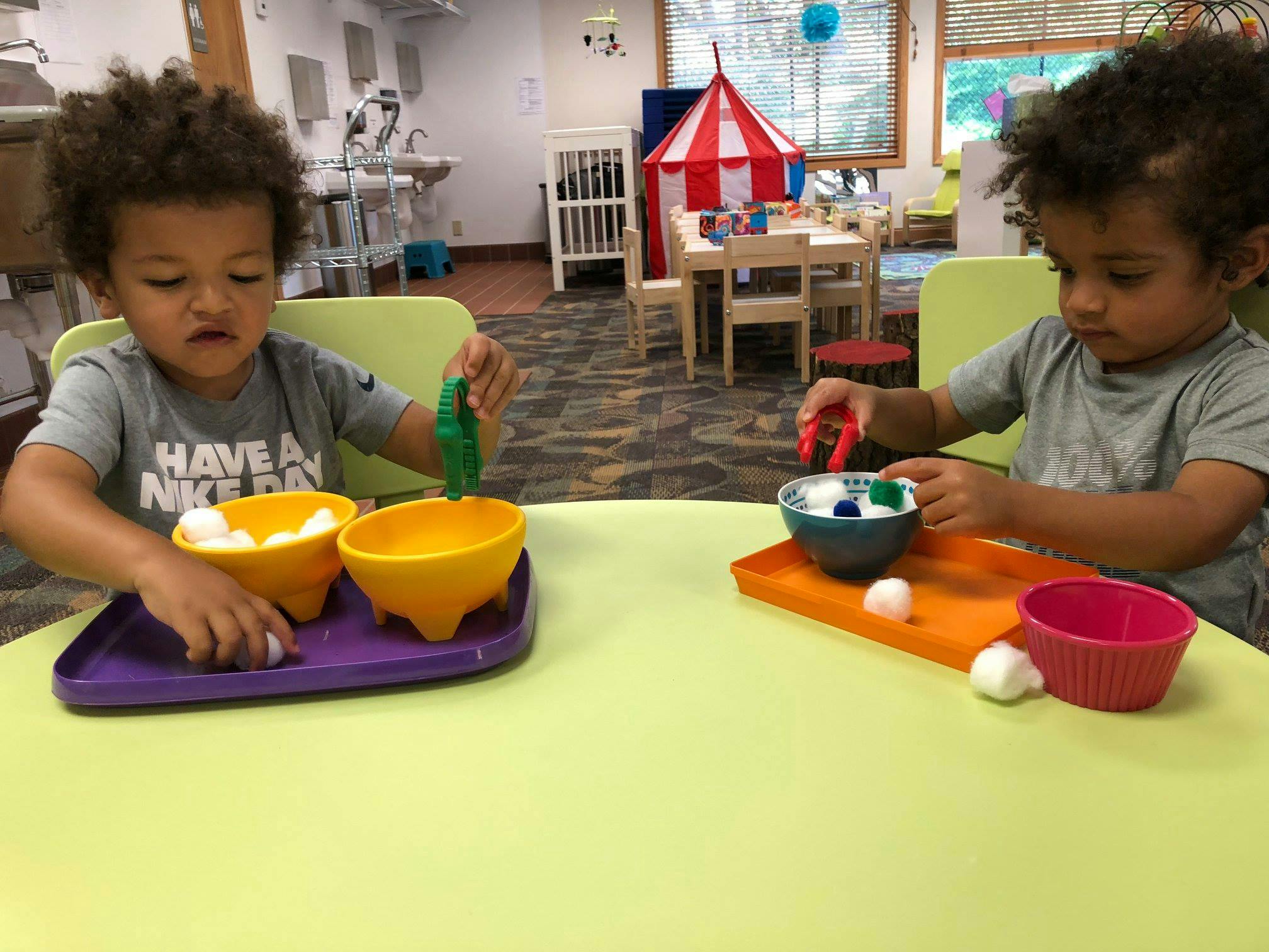 Two children playing with bowls and small white objects at a table