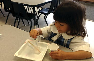 Child mixing something in a container at a table