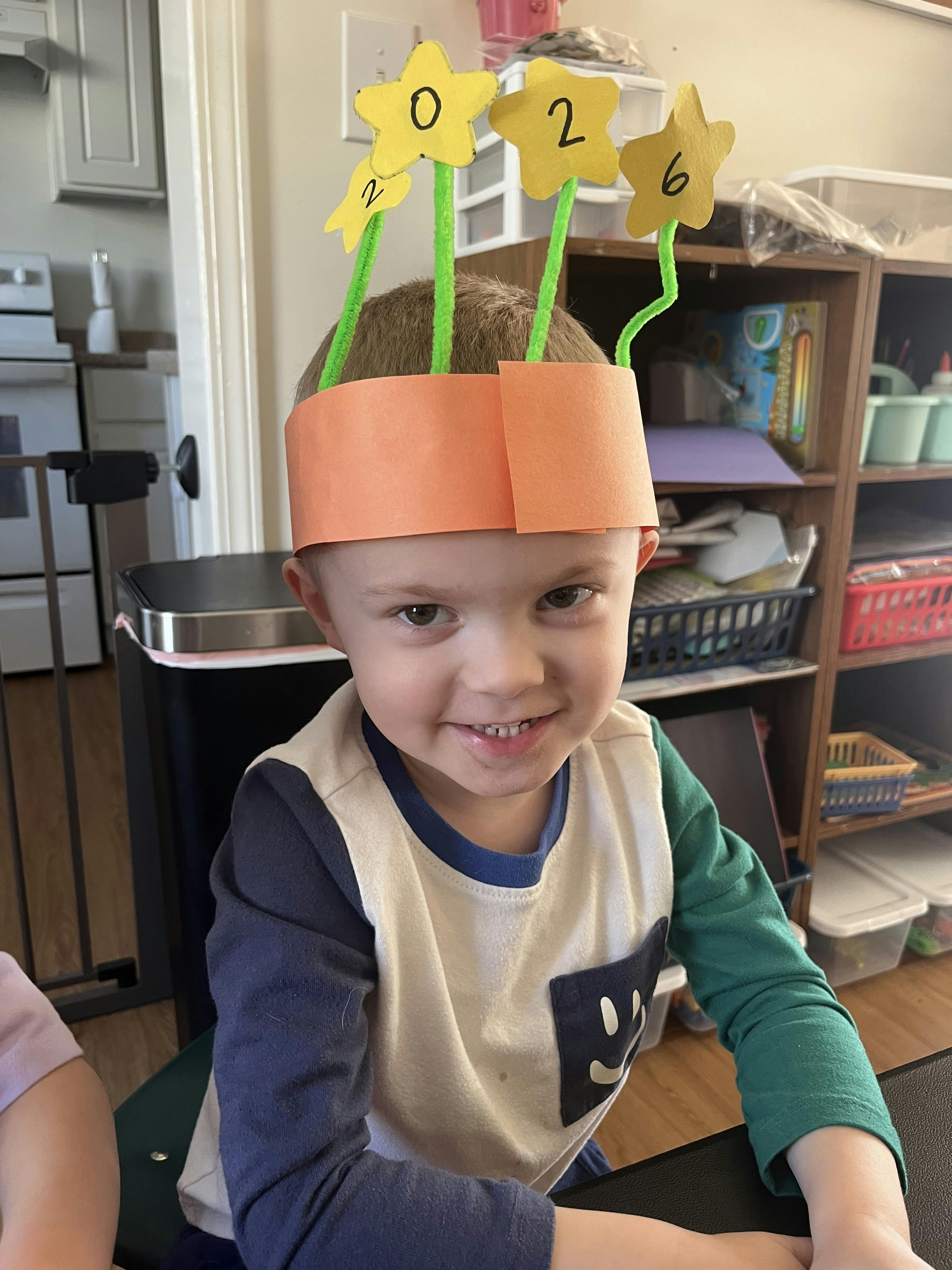 Child wearing a paper crown with stars and numbers 0, 2, and 6