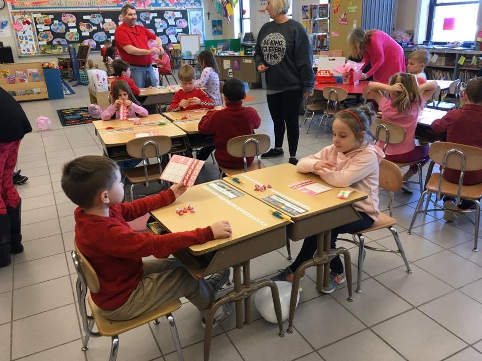 Children and adults in a classroom with children seated at desks