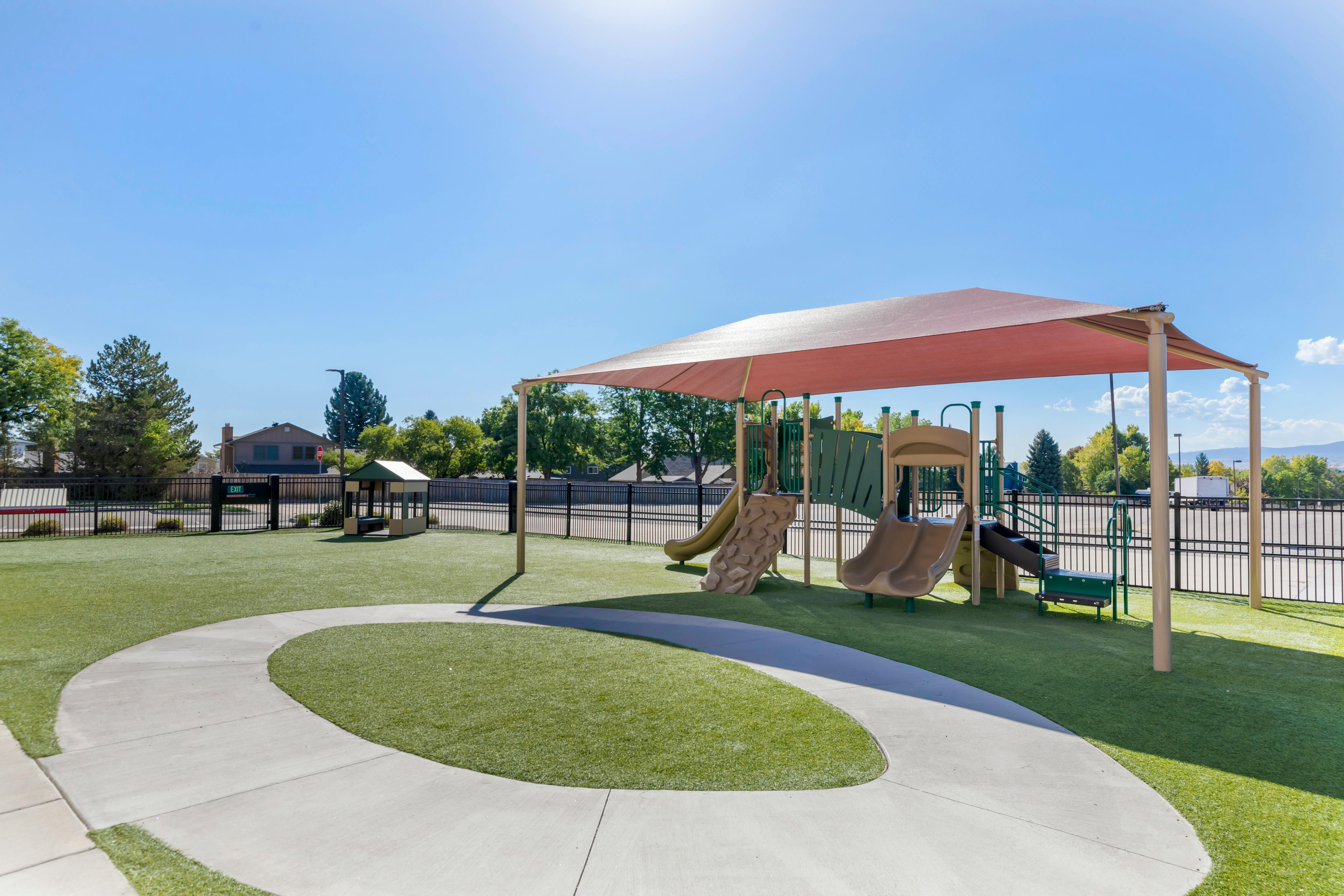 Playground with slides and climbing structures under a large shade canopy