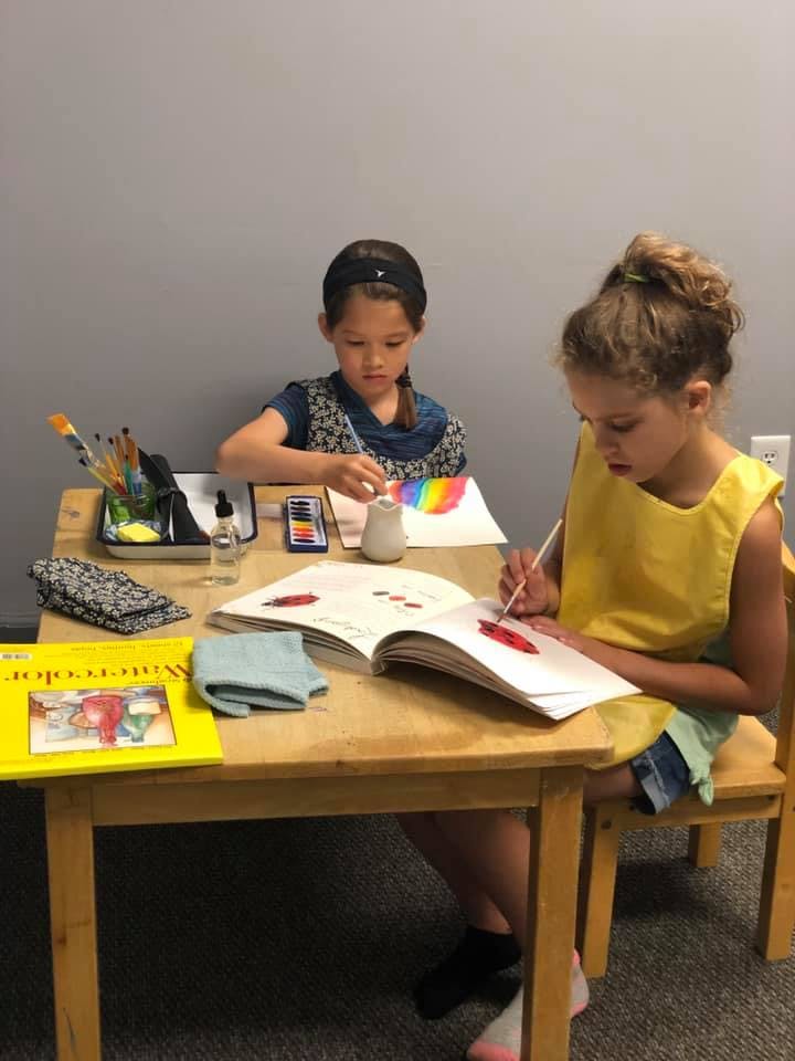 Two children painting at a table