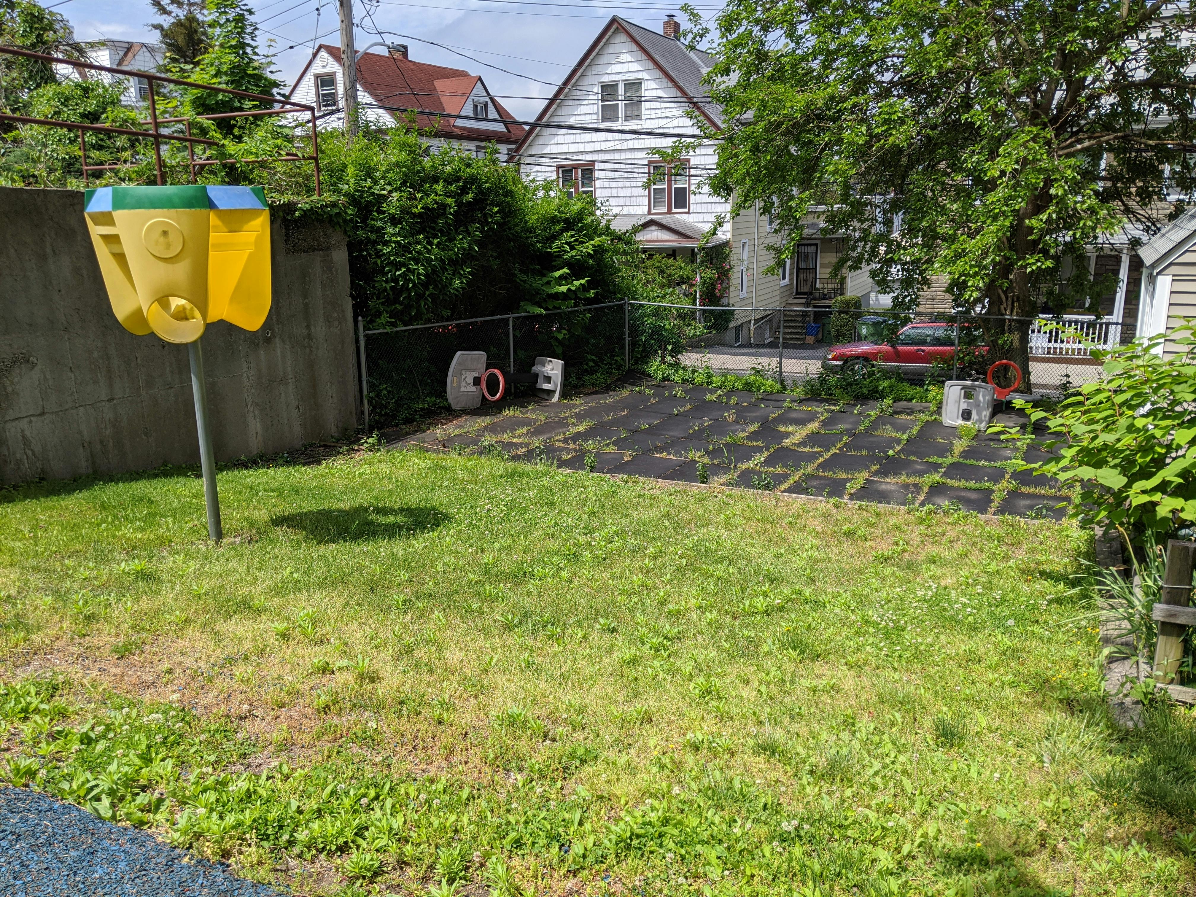 Backyard with a yellow and green basketball hoop and a garden bed