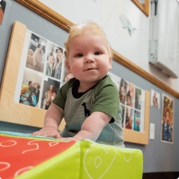 Child in striped shirt and green top looking forward