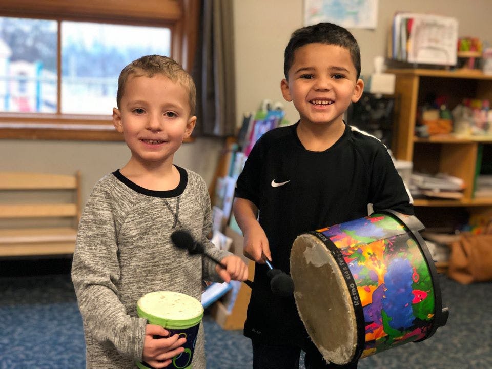 Two children holding drums and drumsticks