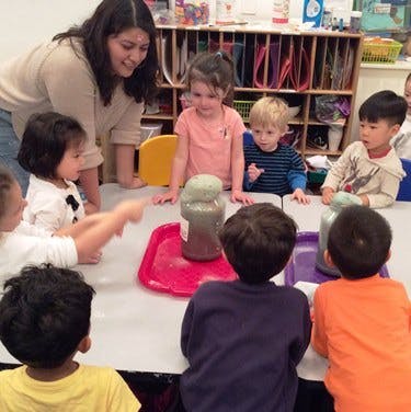 Adult and children gathered around a table with science experiment