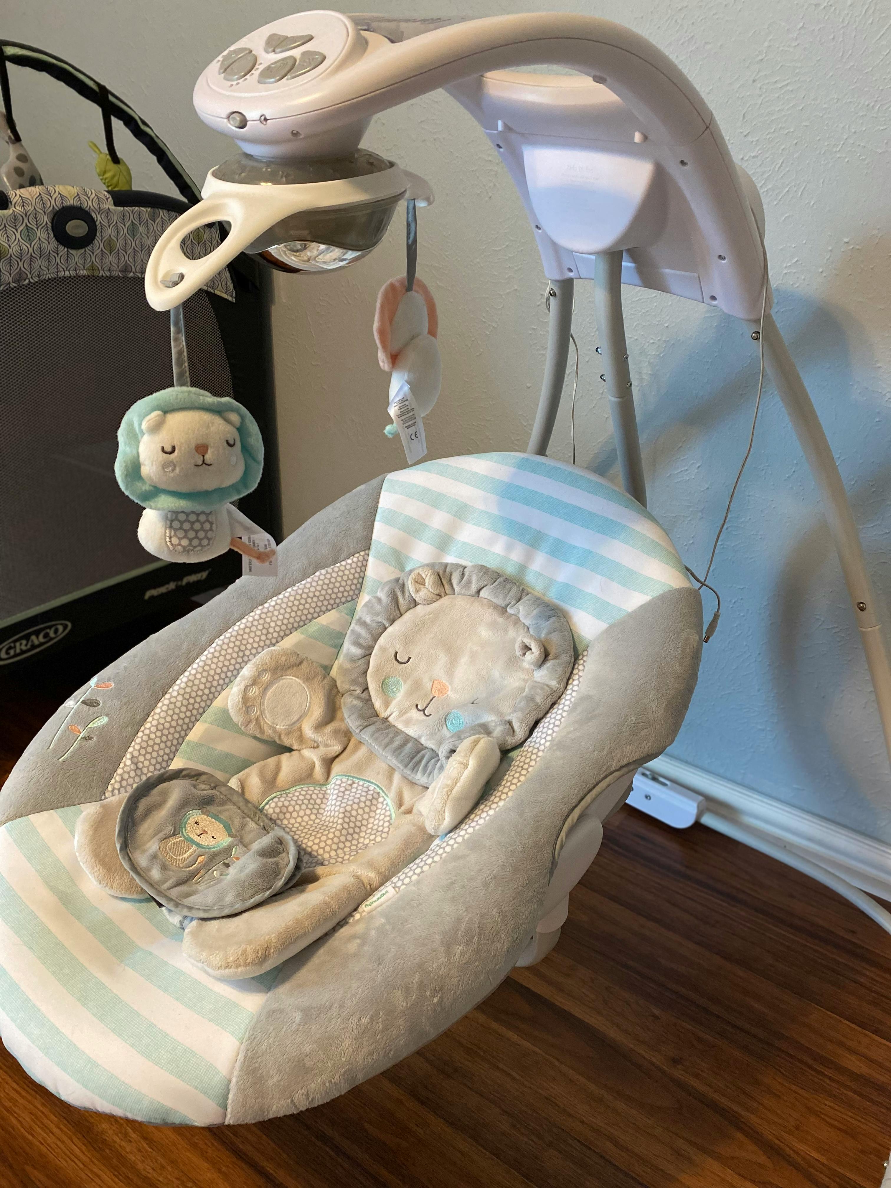 Baby swing with a lion-themed insert and hanging toy