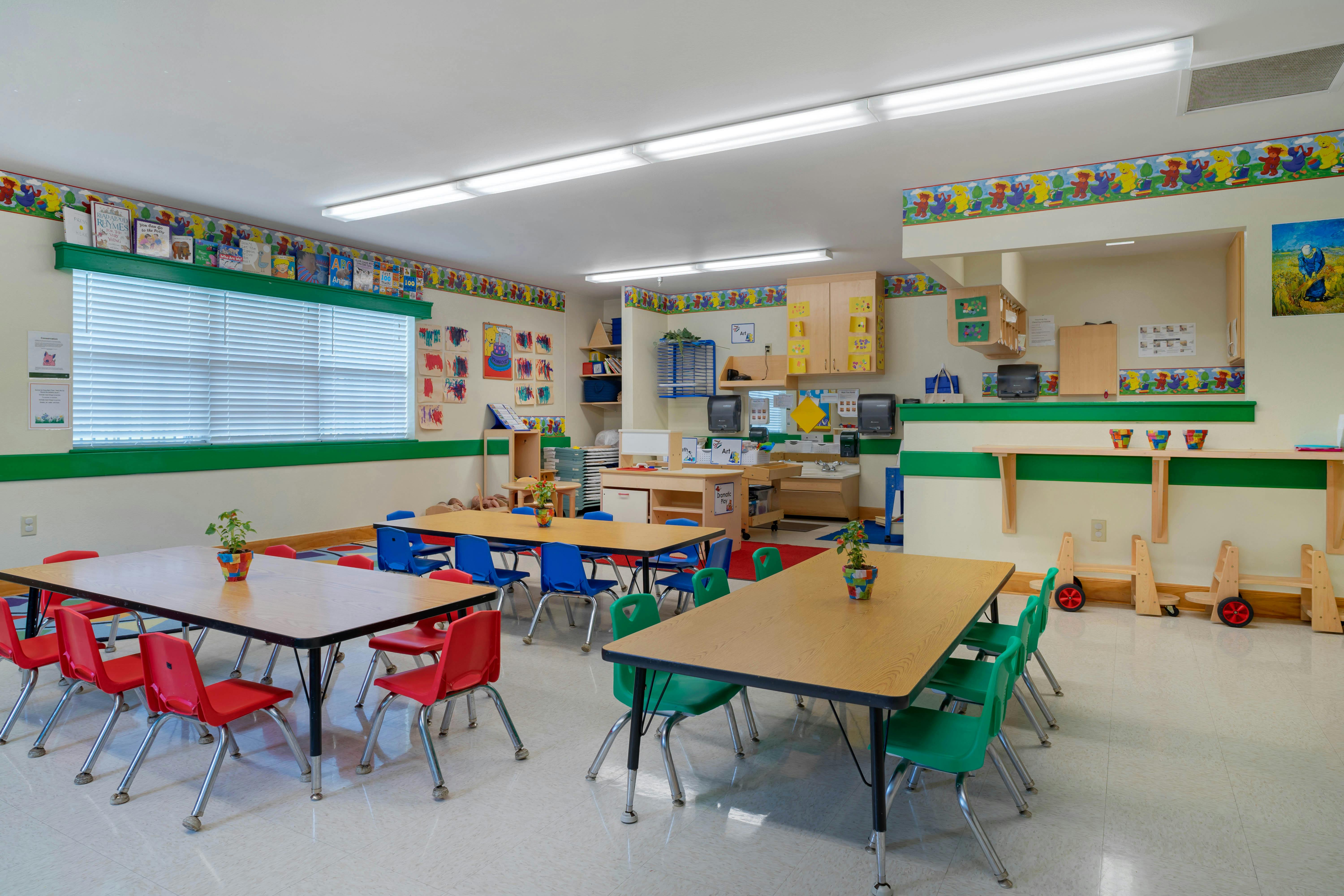 Classroom with tables, colorful chairs, and children's artwork on the walls