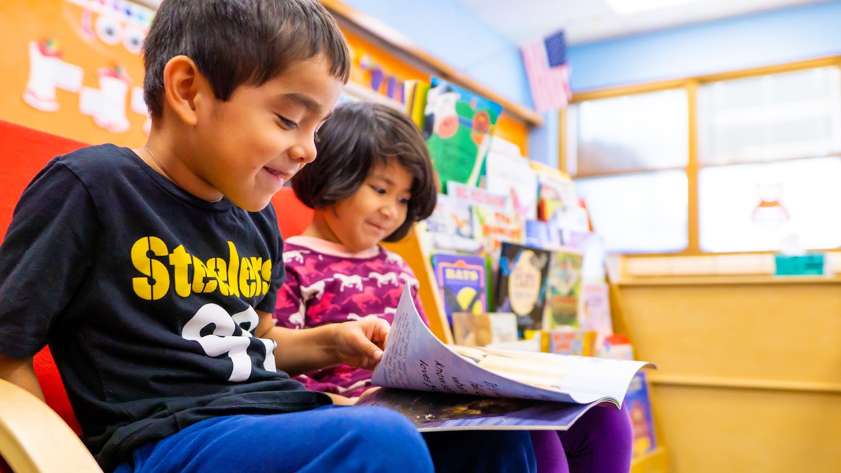 Two children reading a book together in a classroom