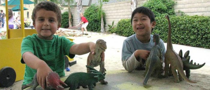 Two children playing with dinosaur toys