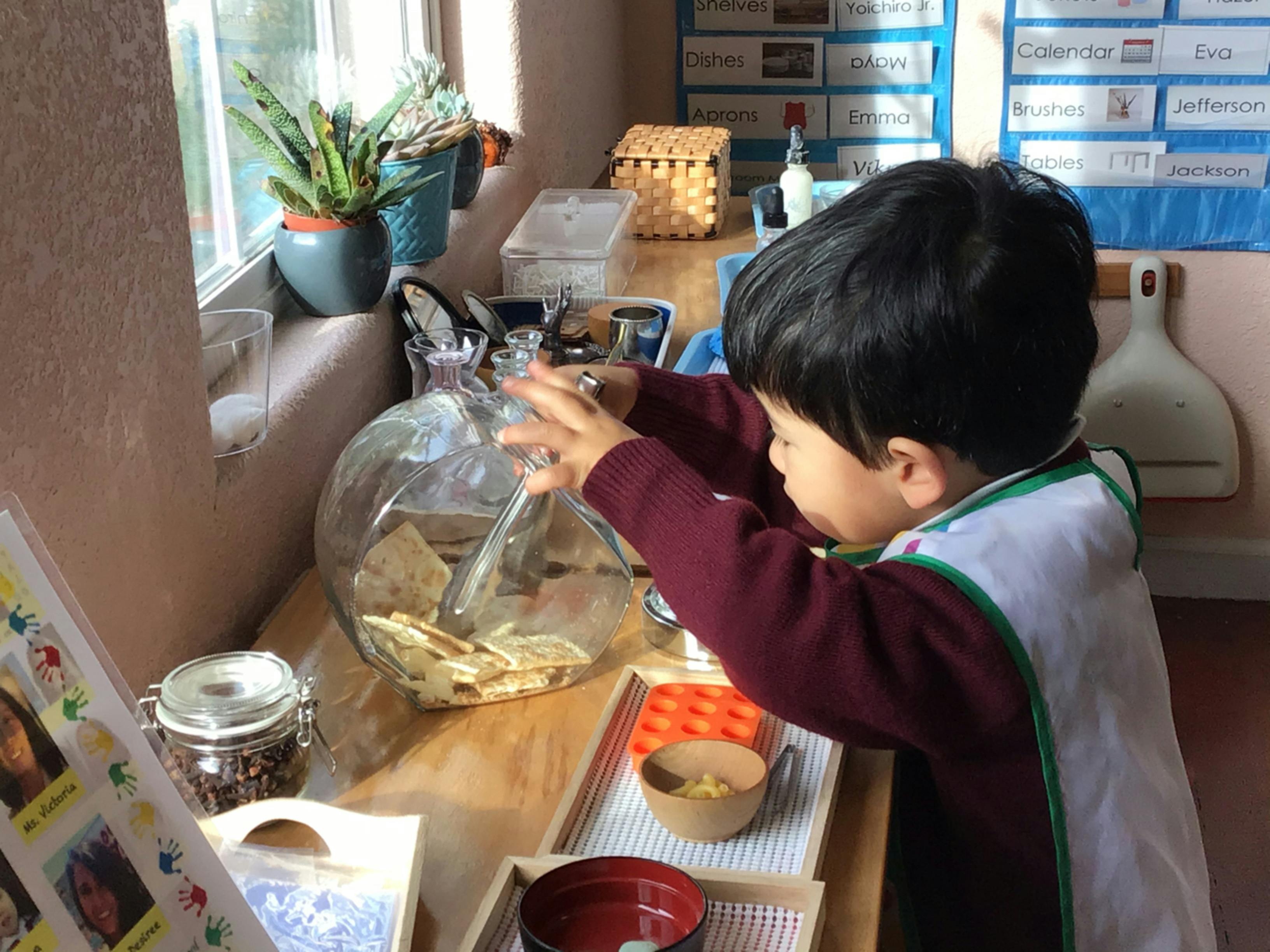 Child reaching into a large glass jar of crackers