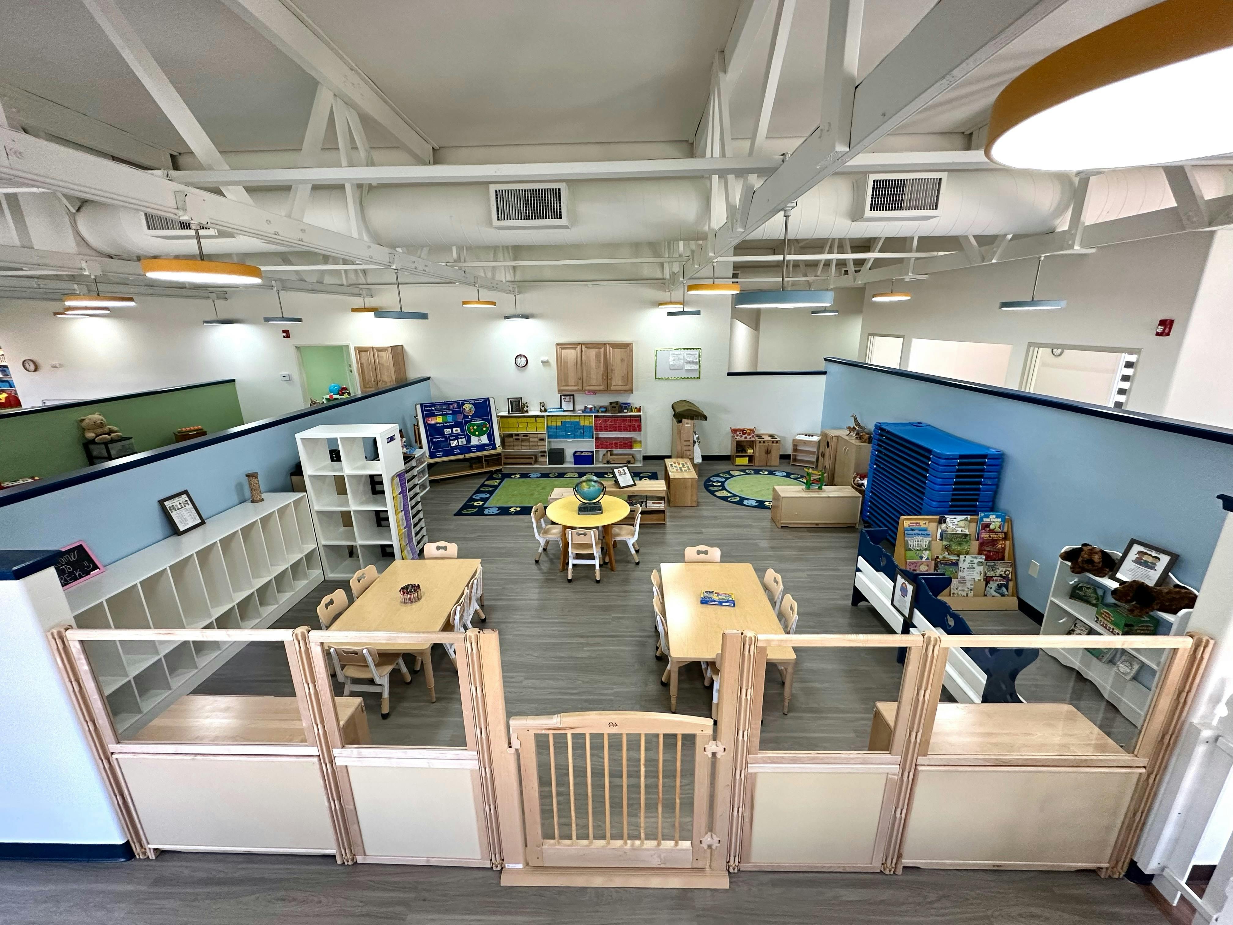 Empty classroom with small tables and chairs, separated play areas