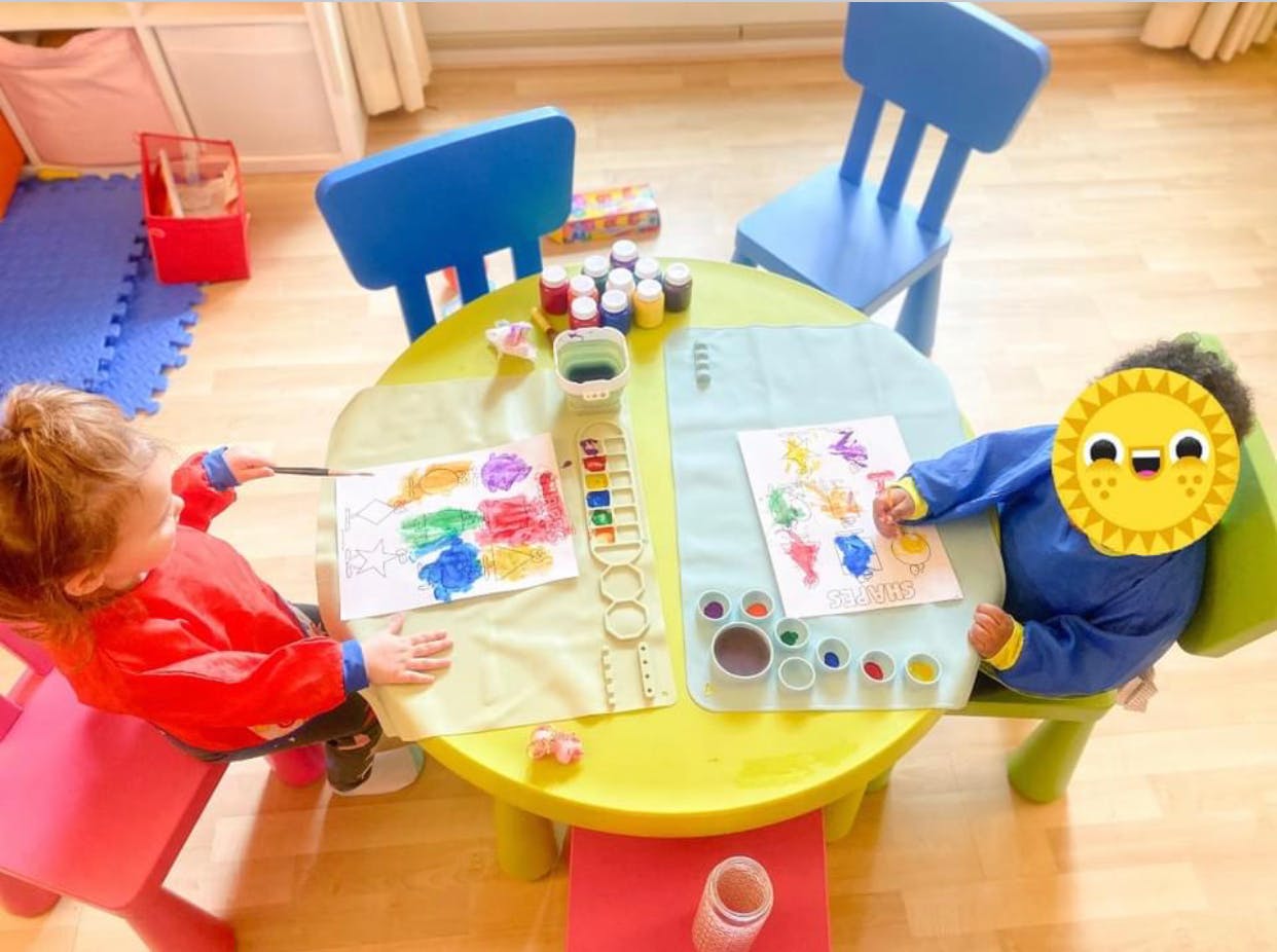 Two children painting at a small table