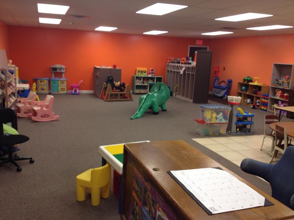 Playroom with orange walls, toys, and a green dinosaur