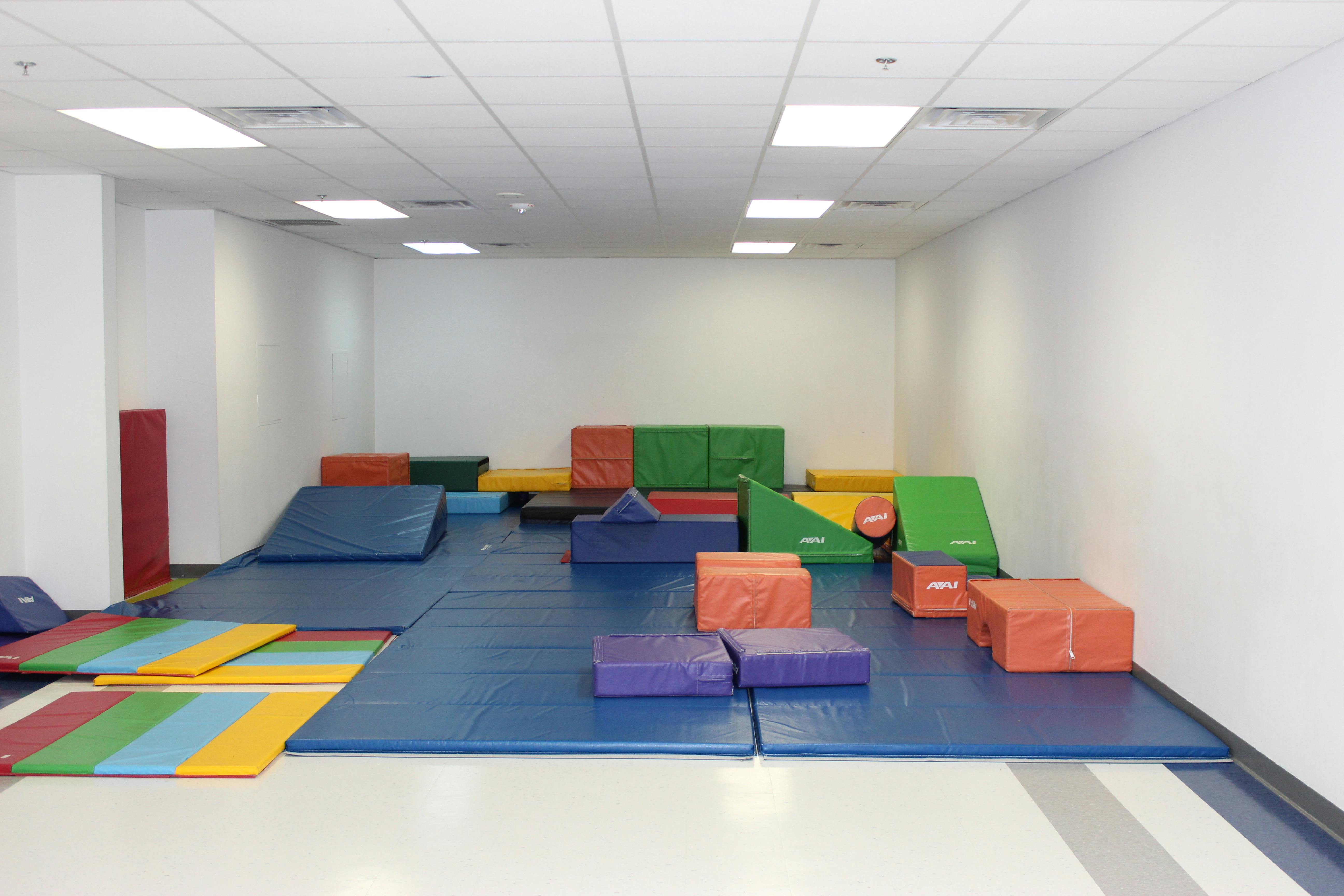 Indoor play area with colorful soft mats and climbing blocks