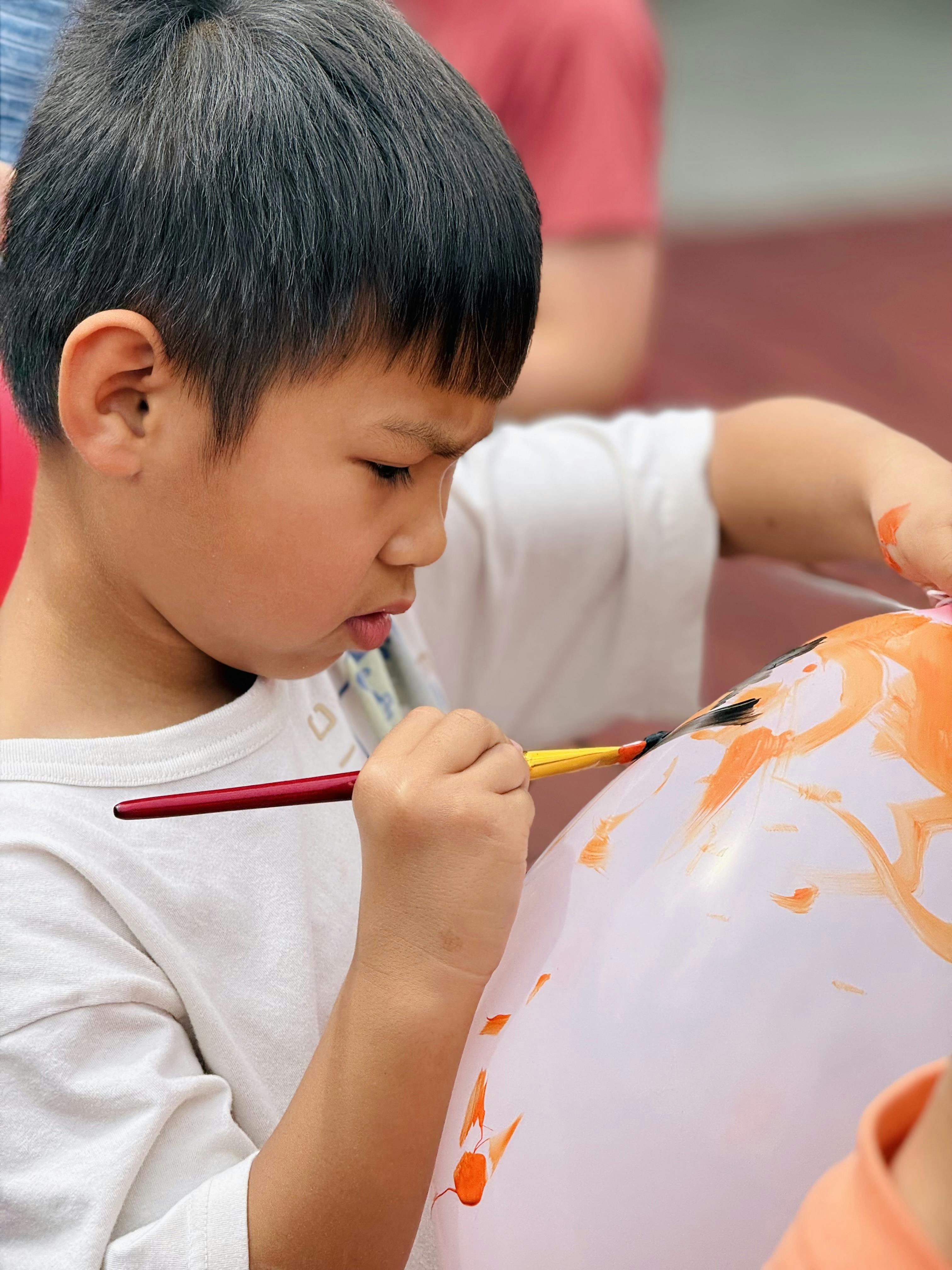 Child painting on a white balloon with a paintbrush