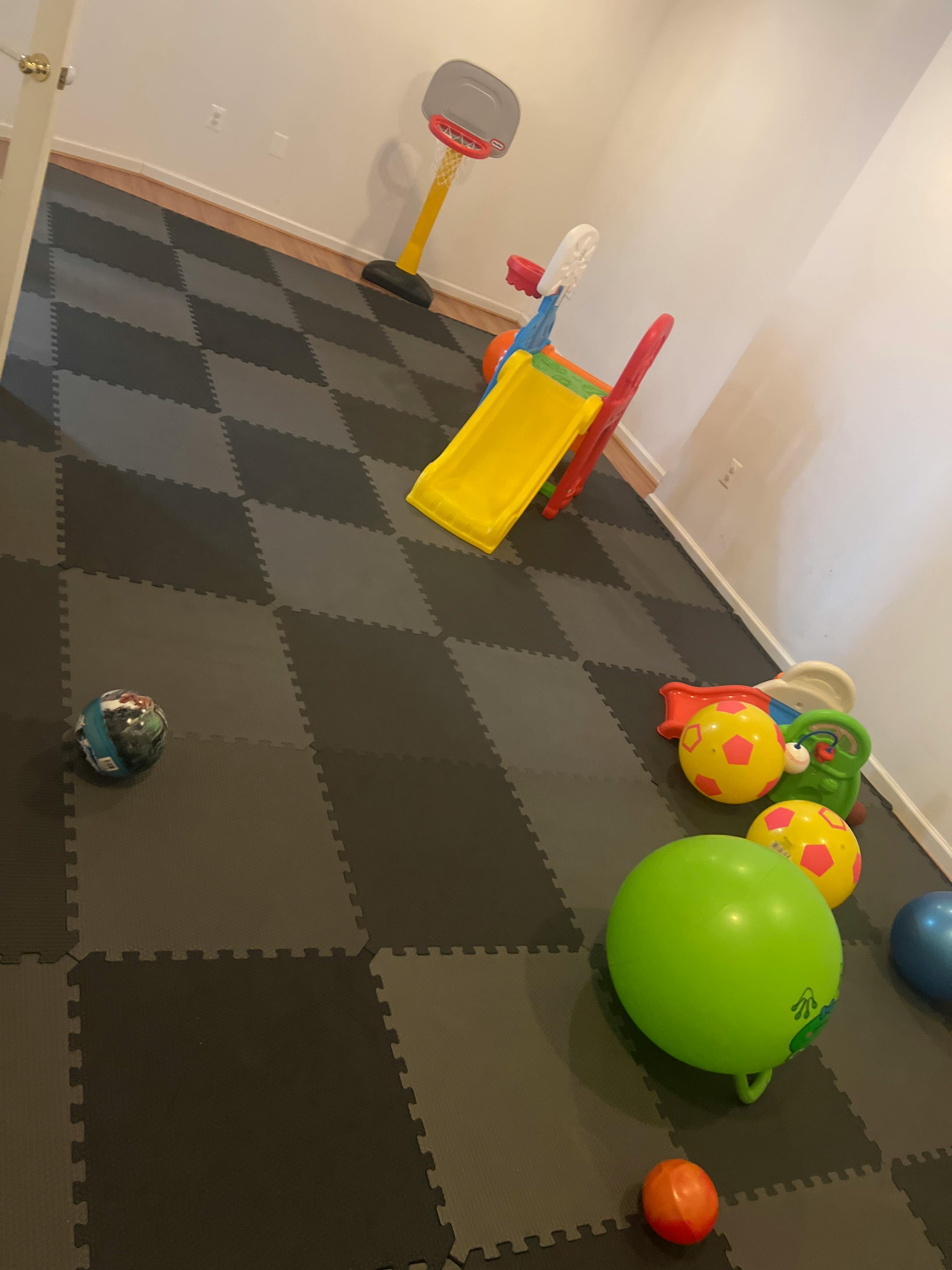 Playroom with checkerboard floor mats, a small slide, and various balls