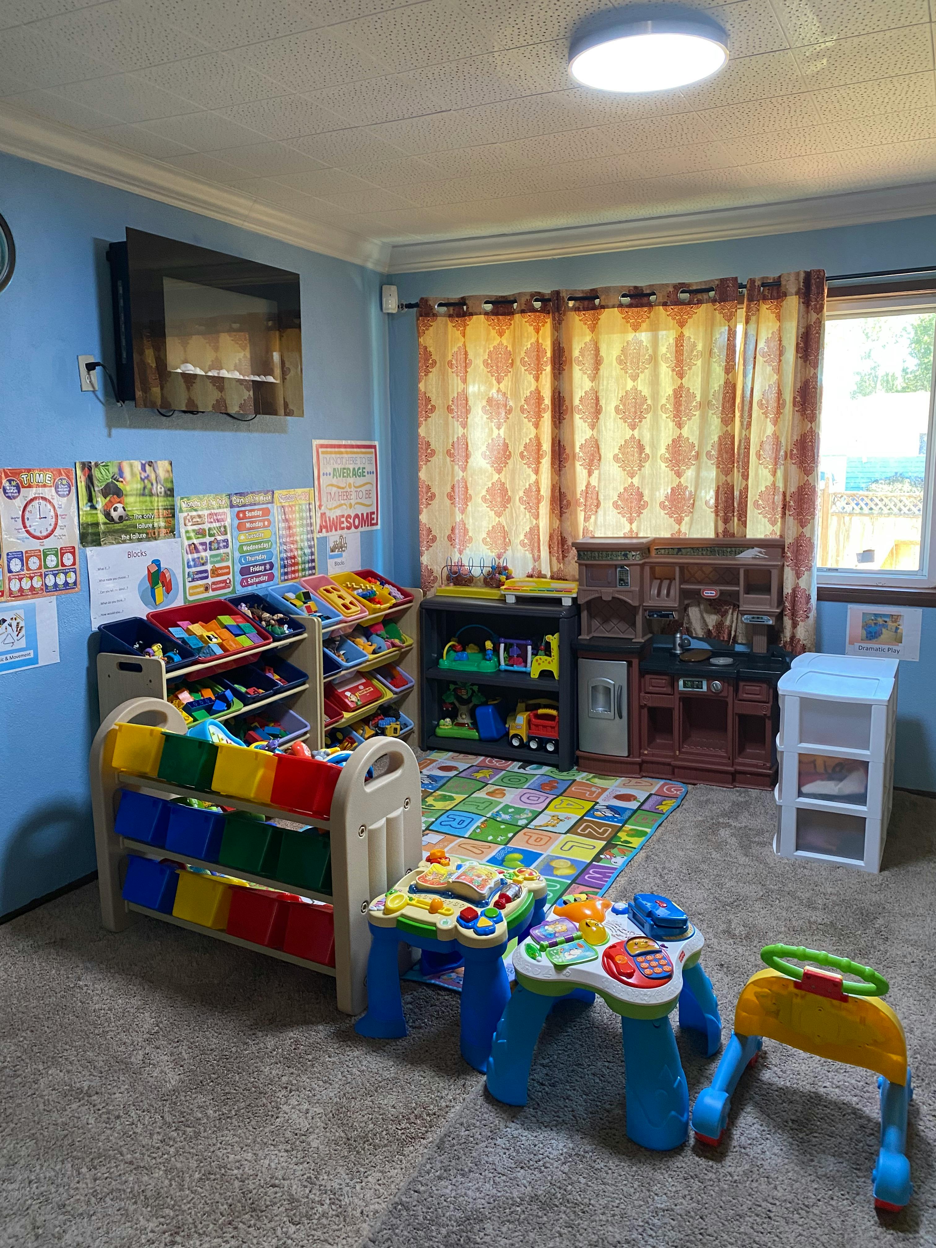 Playroom with toy storage, play kitchen, and activity tables