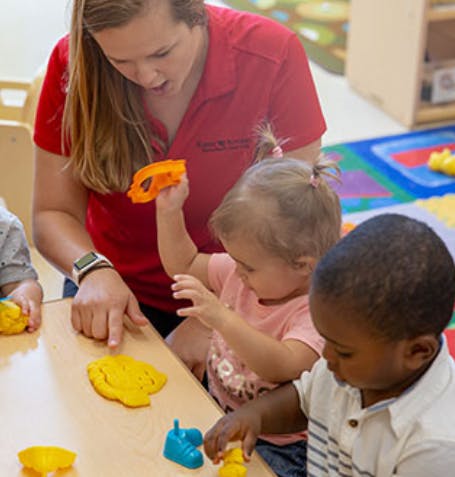 Adult and two children playing with toys at a table