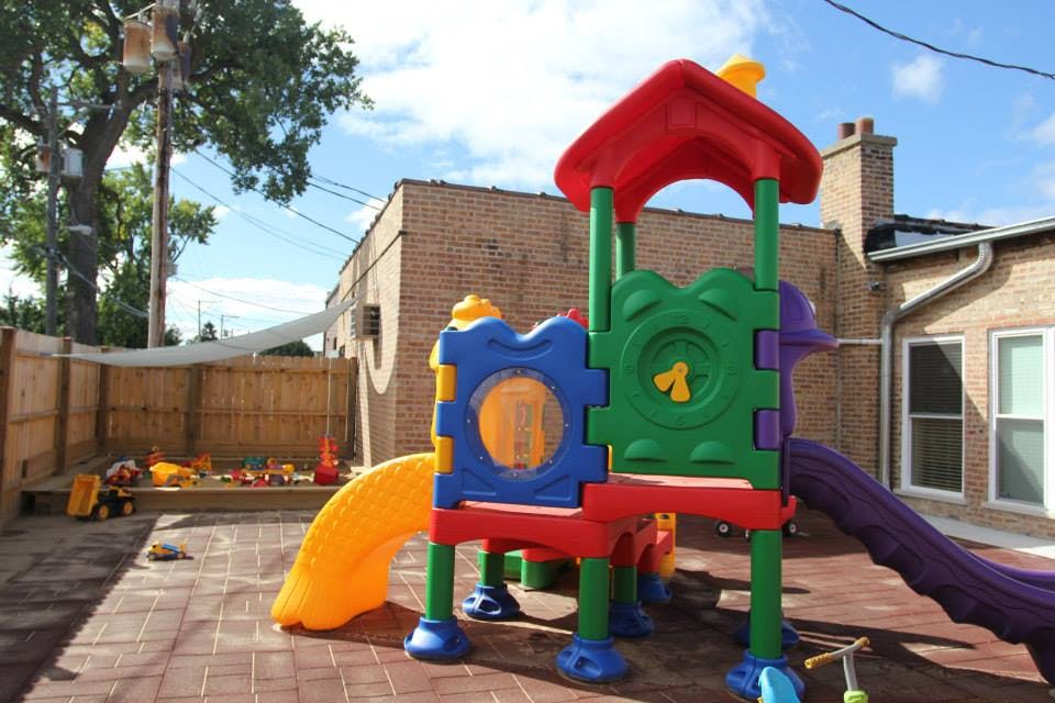 Colorful playground structure with slides and a sandbox in the background
