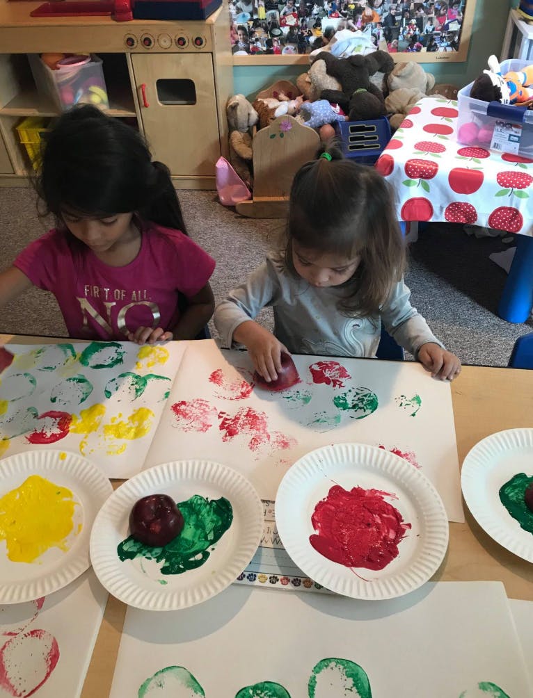 Two children doing potato printing with paint