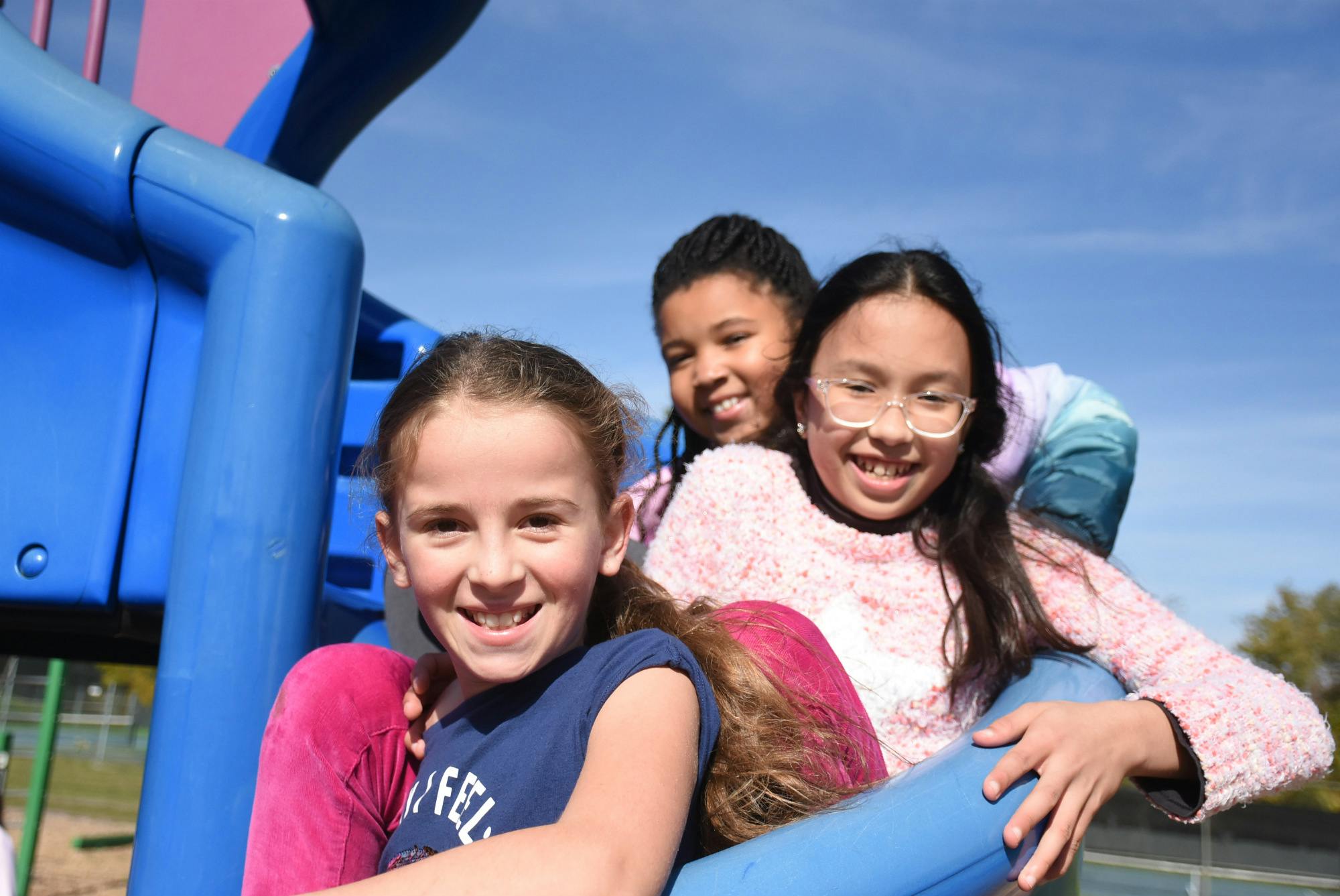 Three children on a blue playground structure