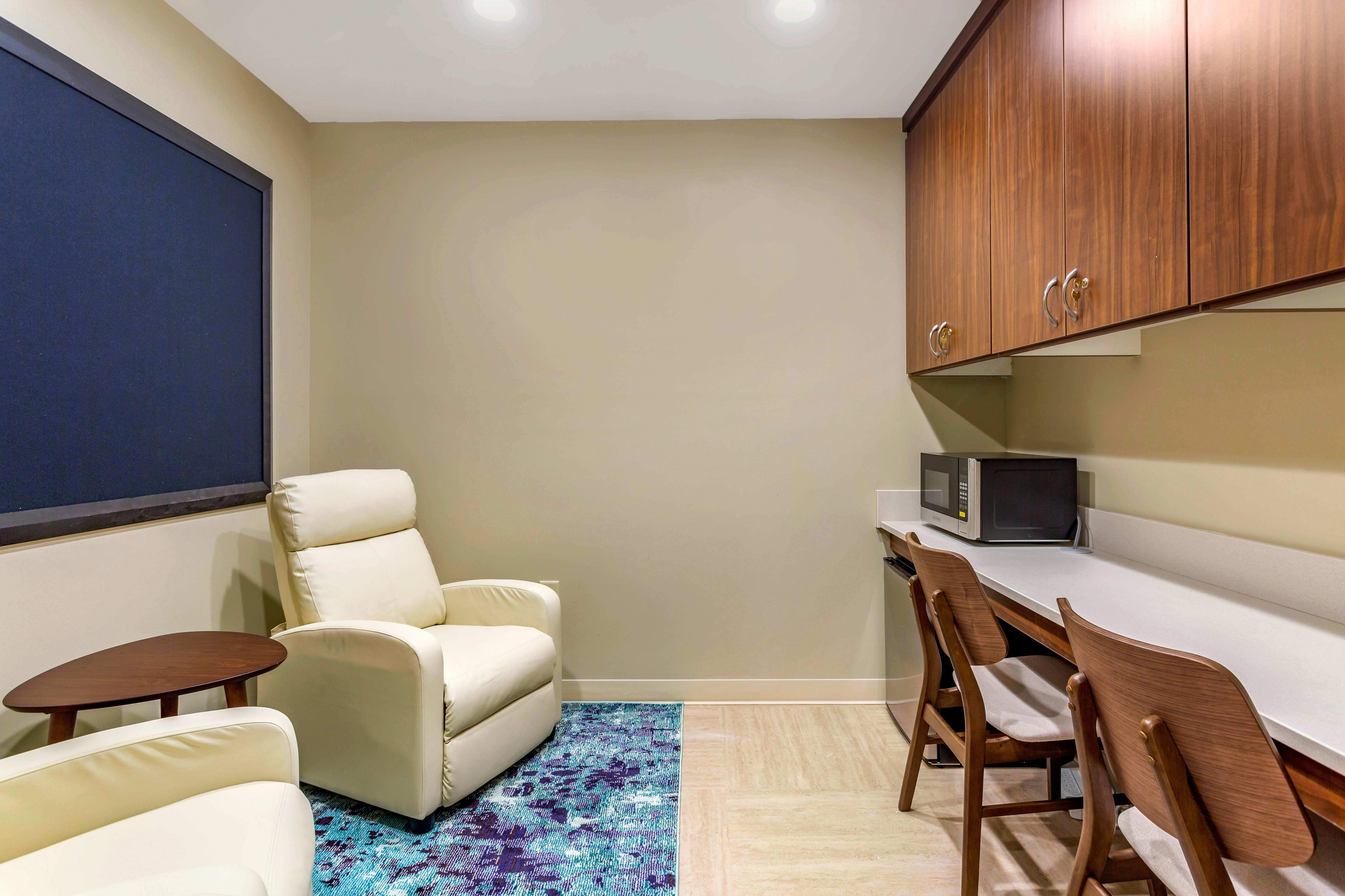 Lounge area with two recliners and a small table on a rug next to a built-in counter with a microwave and two chairs