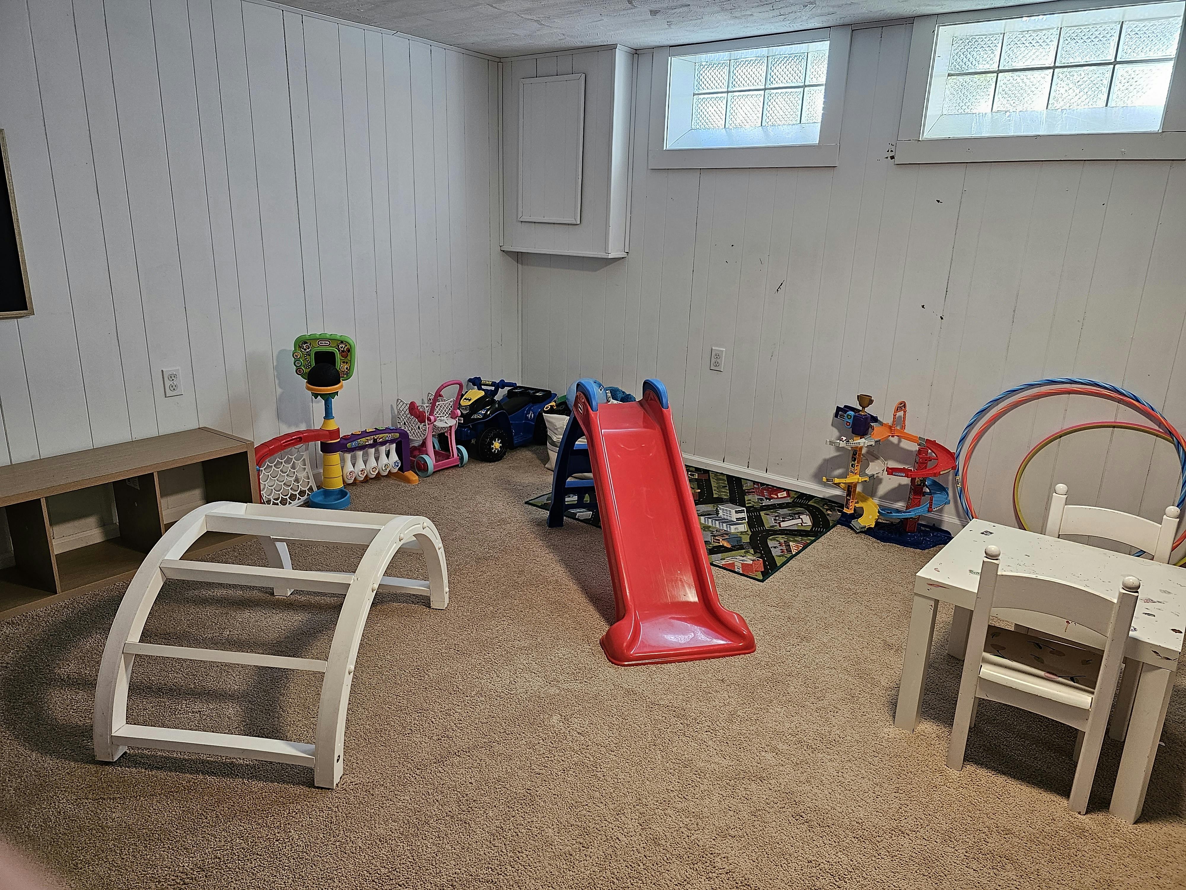 Playroom with a red slide, white climbing arch, and small table and chairs