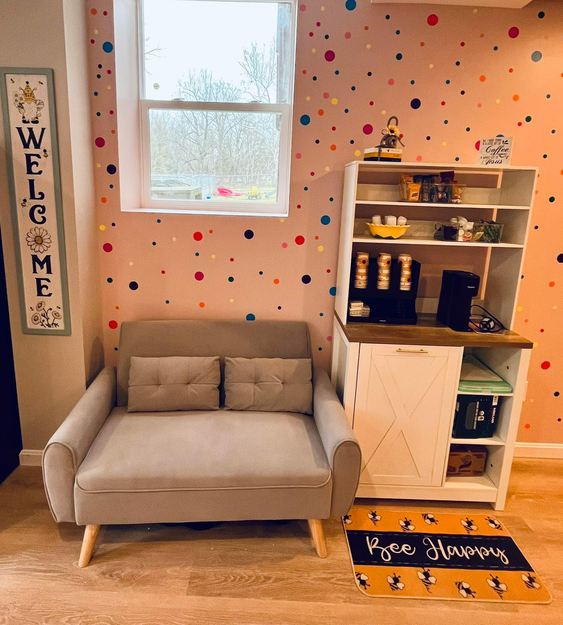 Small gray sofa next to a white cabinet with a coffee maker