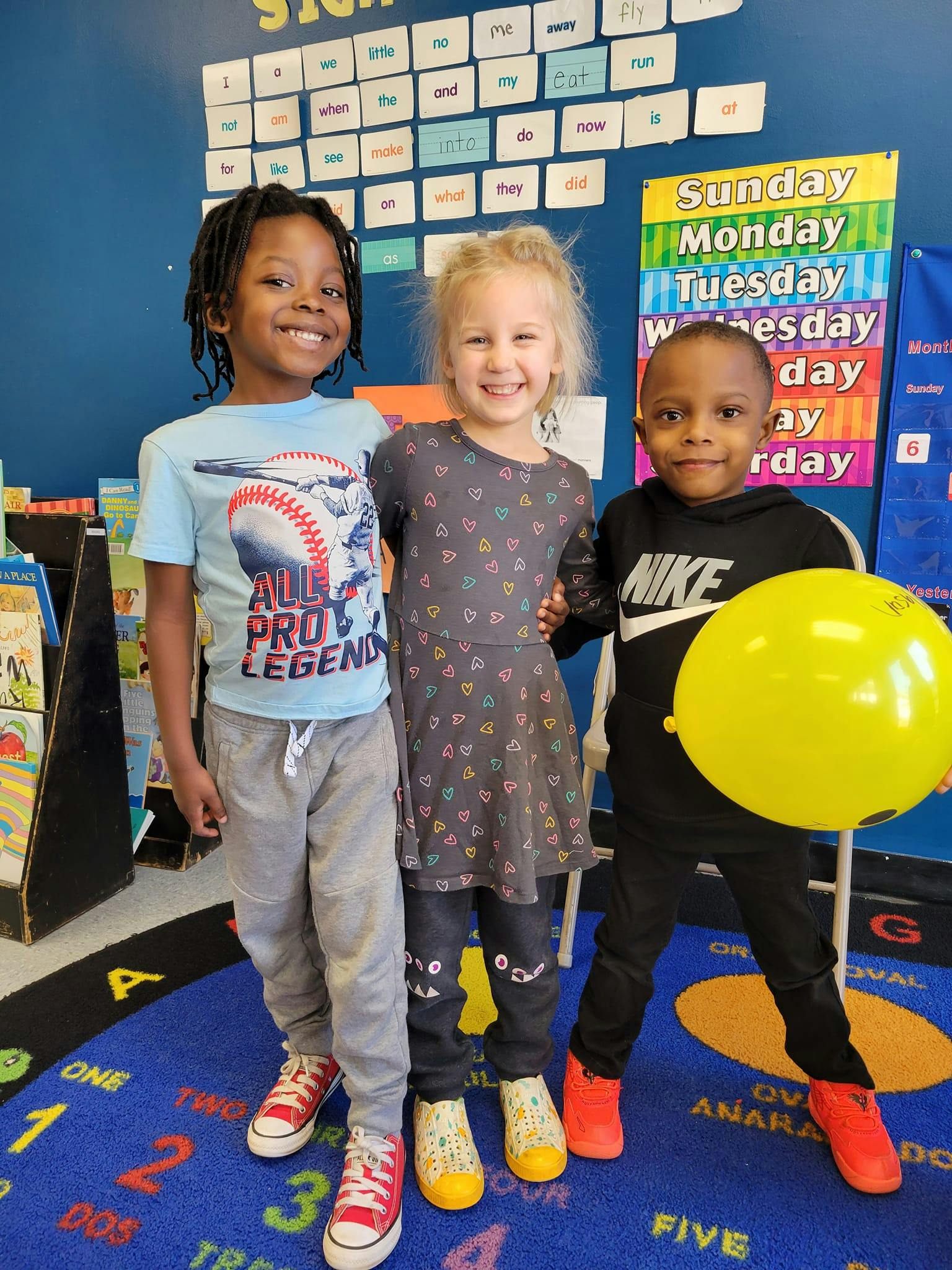 Three children standing together in a classroom