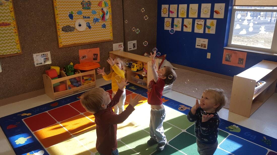 Children playing with bubbles in a classroom