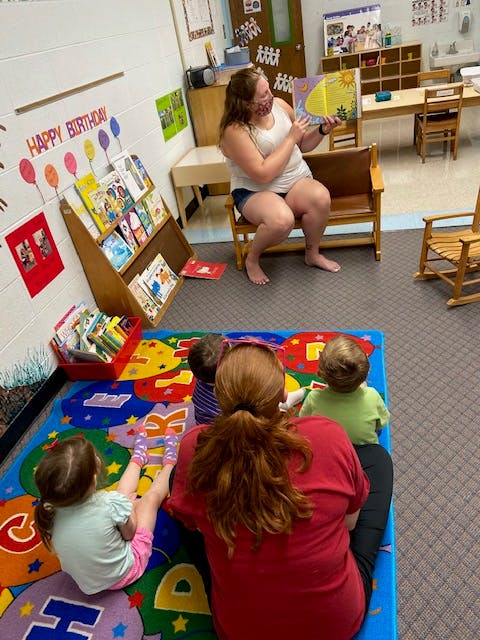 Person reading a book to children in a classroom