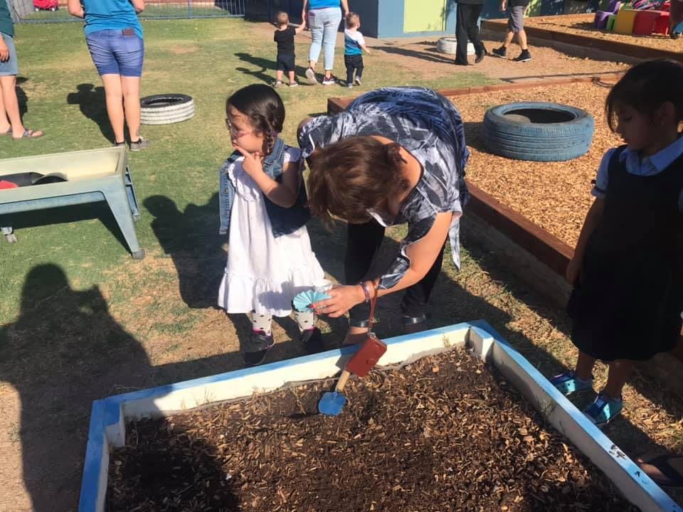 Adult and child planting in a raised garden bed