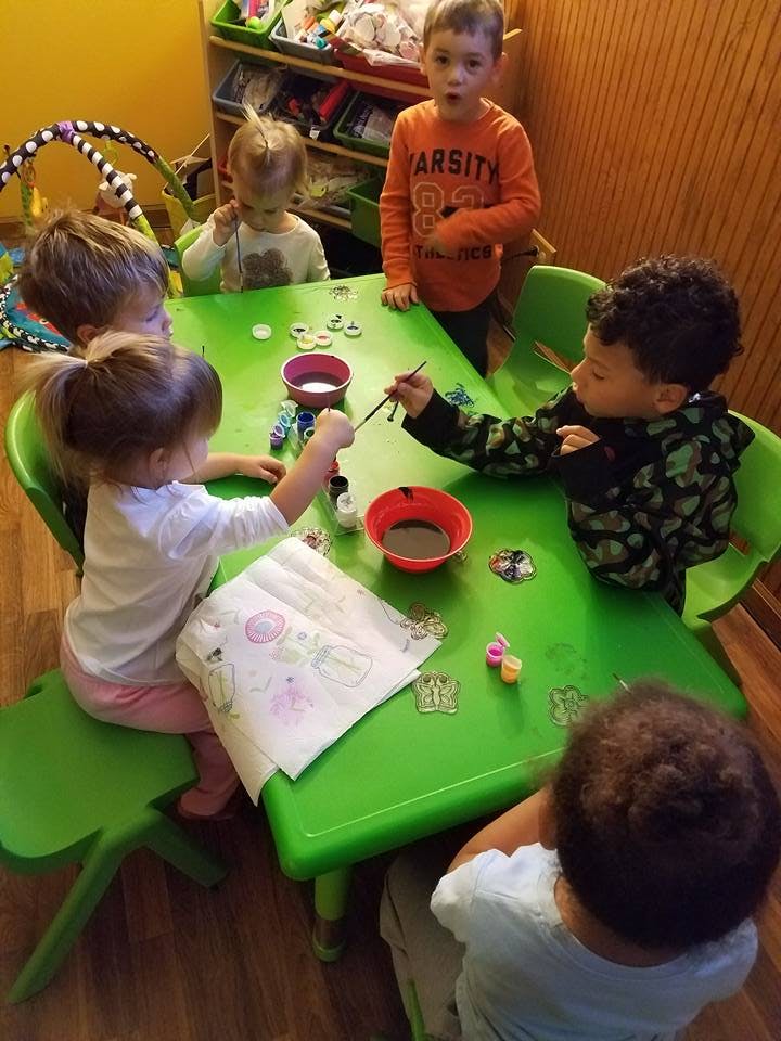Children painting at a green table