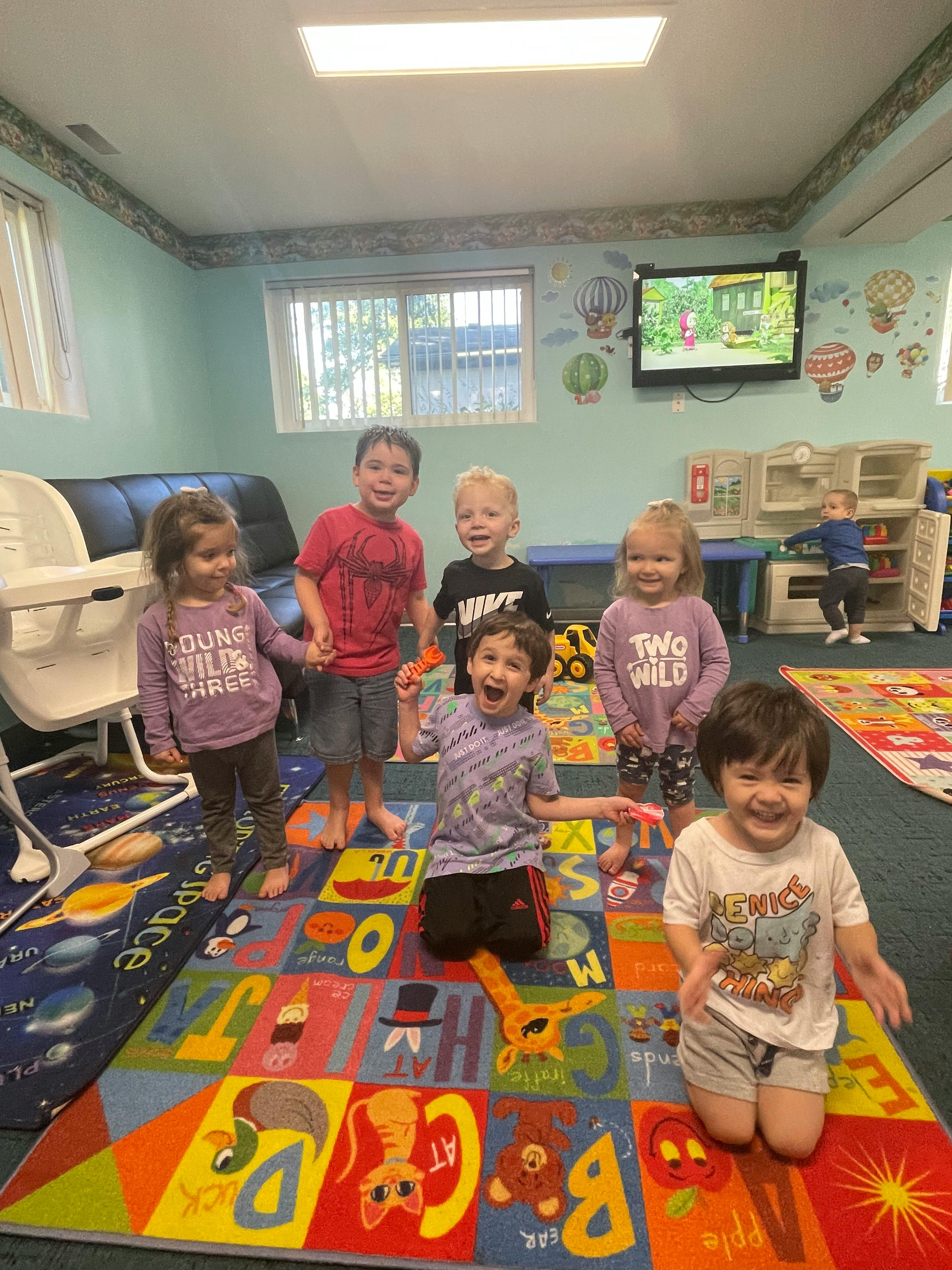 Group of children standing on a colorful alphabet rug