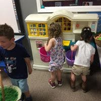 Three children playing with toy house and buckets