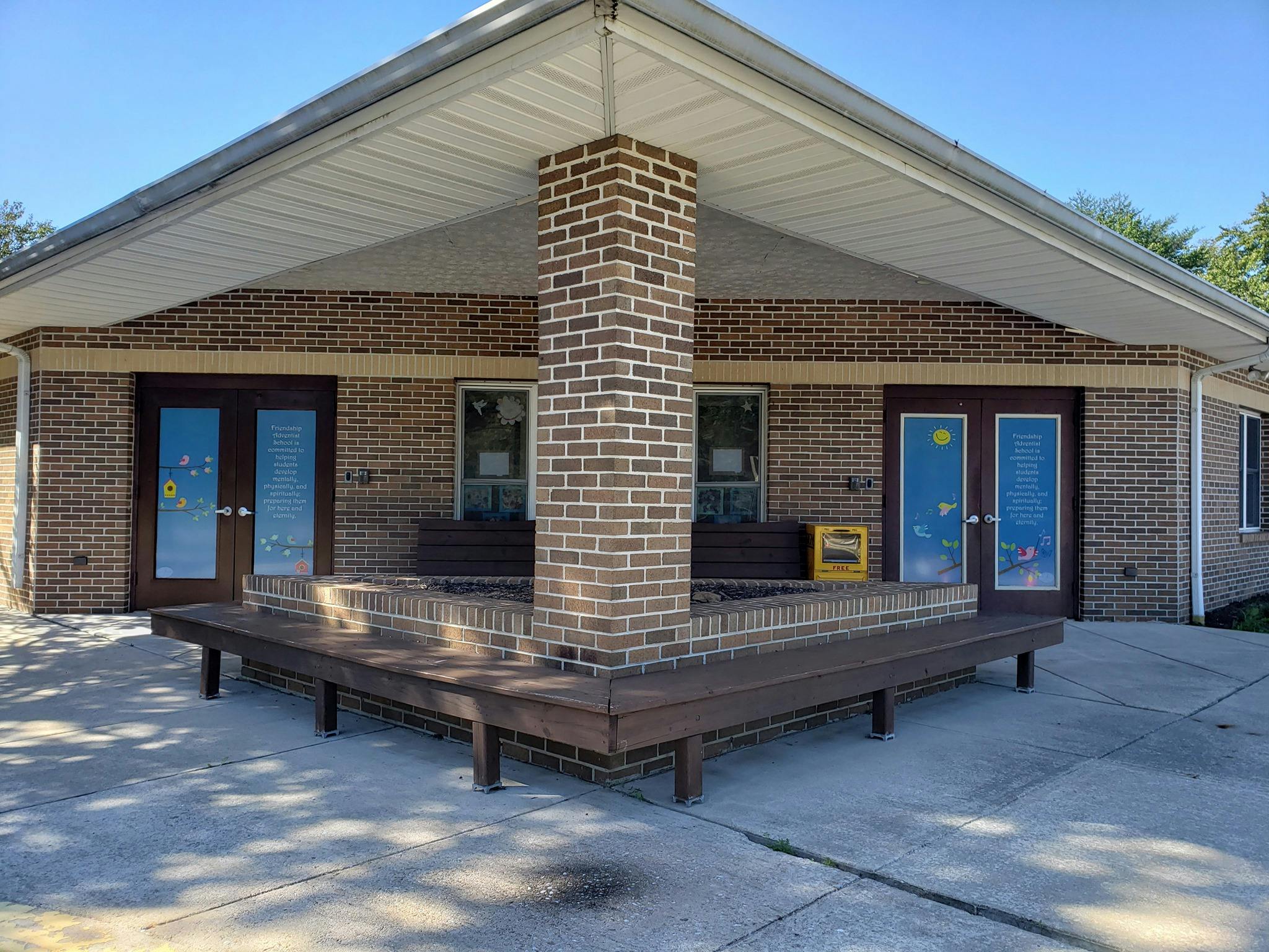 Brick school entrance with a wrap-around wooden bench