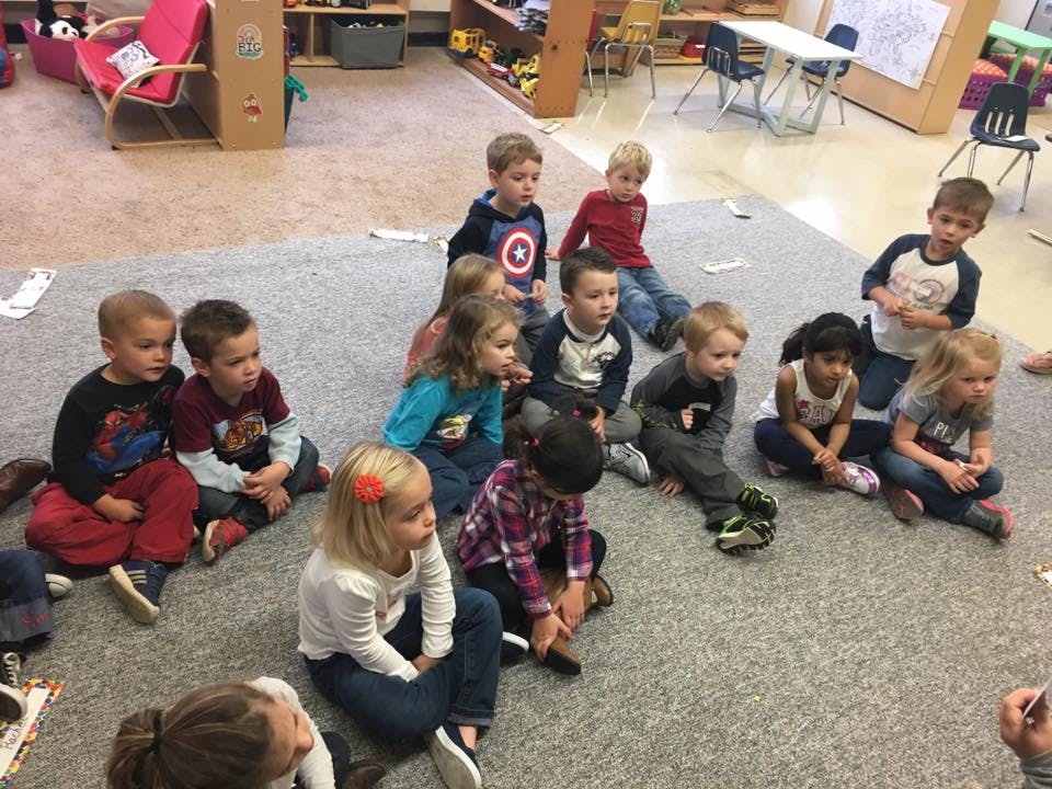 Group of children sitting on a rug in a classroom