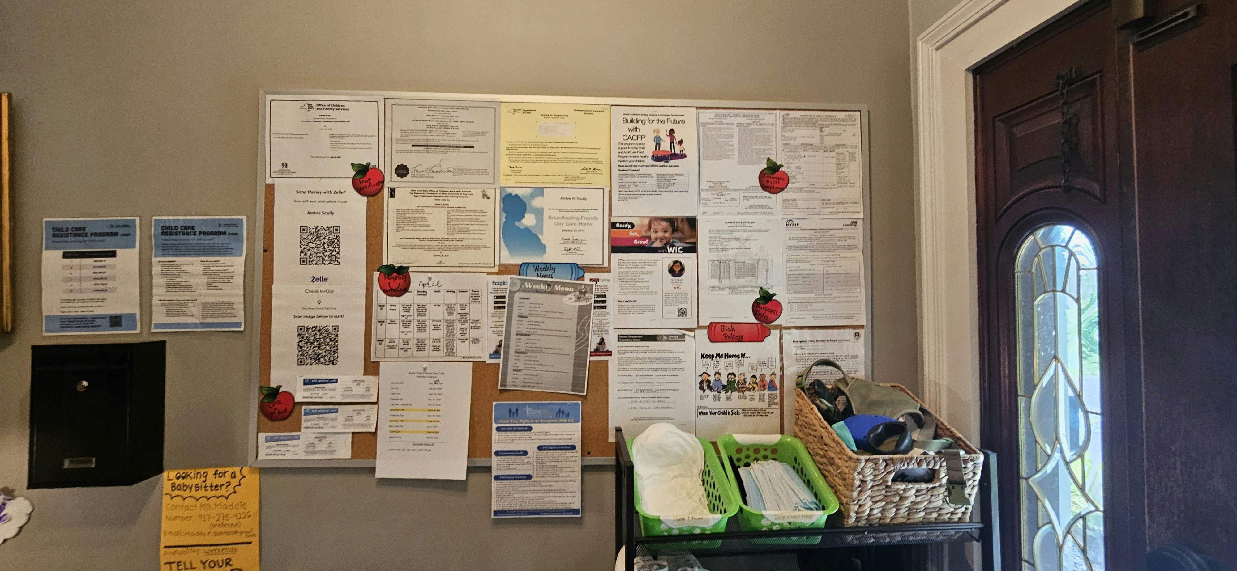 Bulletin board with various documents, QR codes, and a weekly menu next to a door