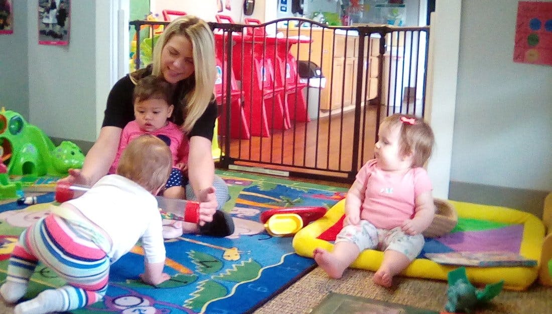 Person sitting on floor with two children, one child crawling, one child sitting