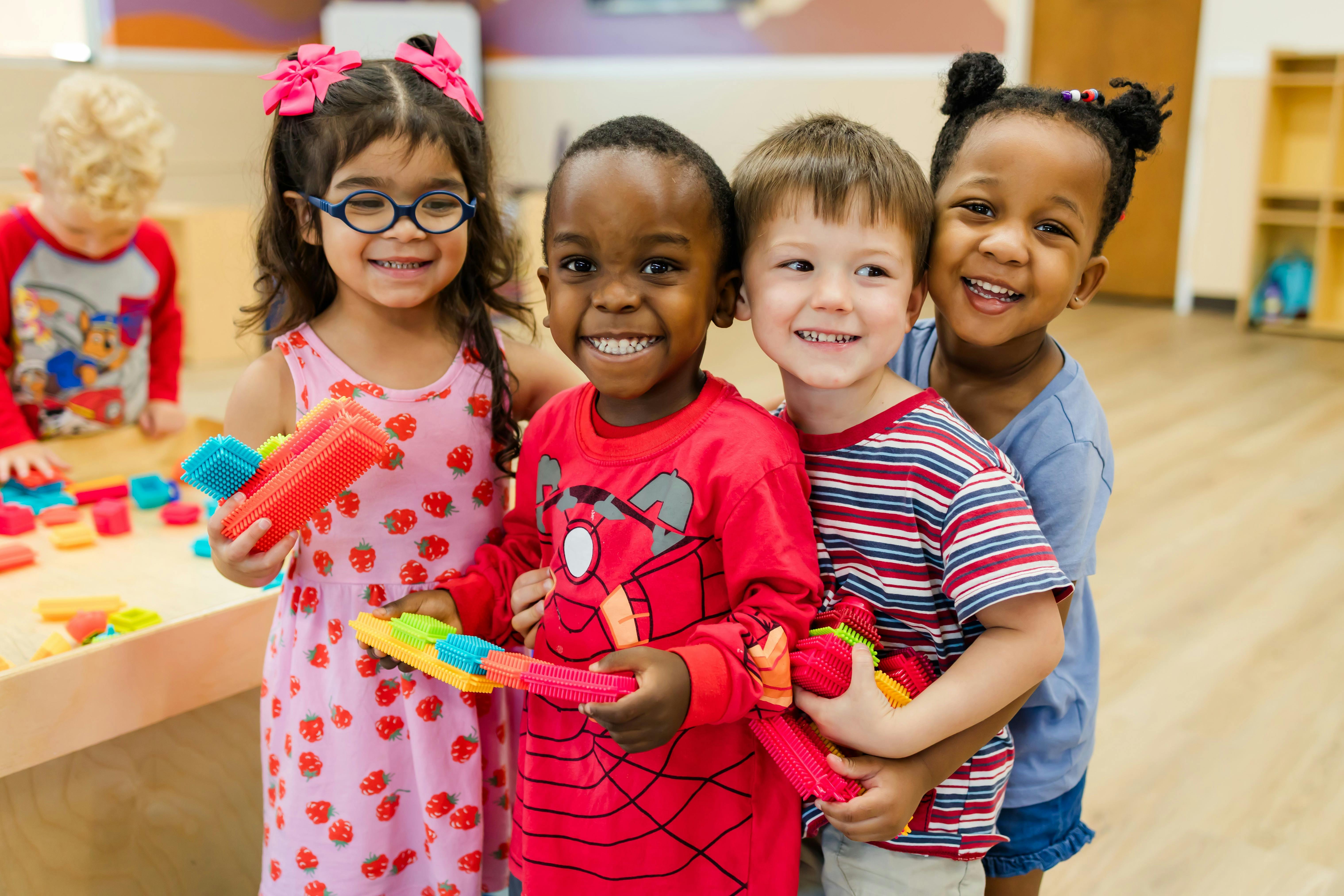 Four children standing together in a classroom