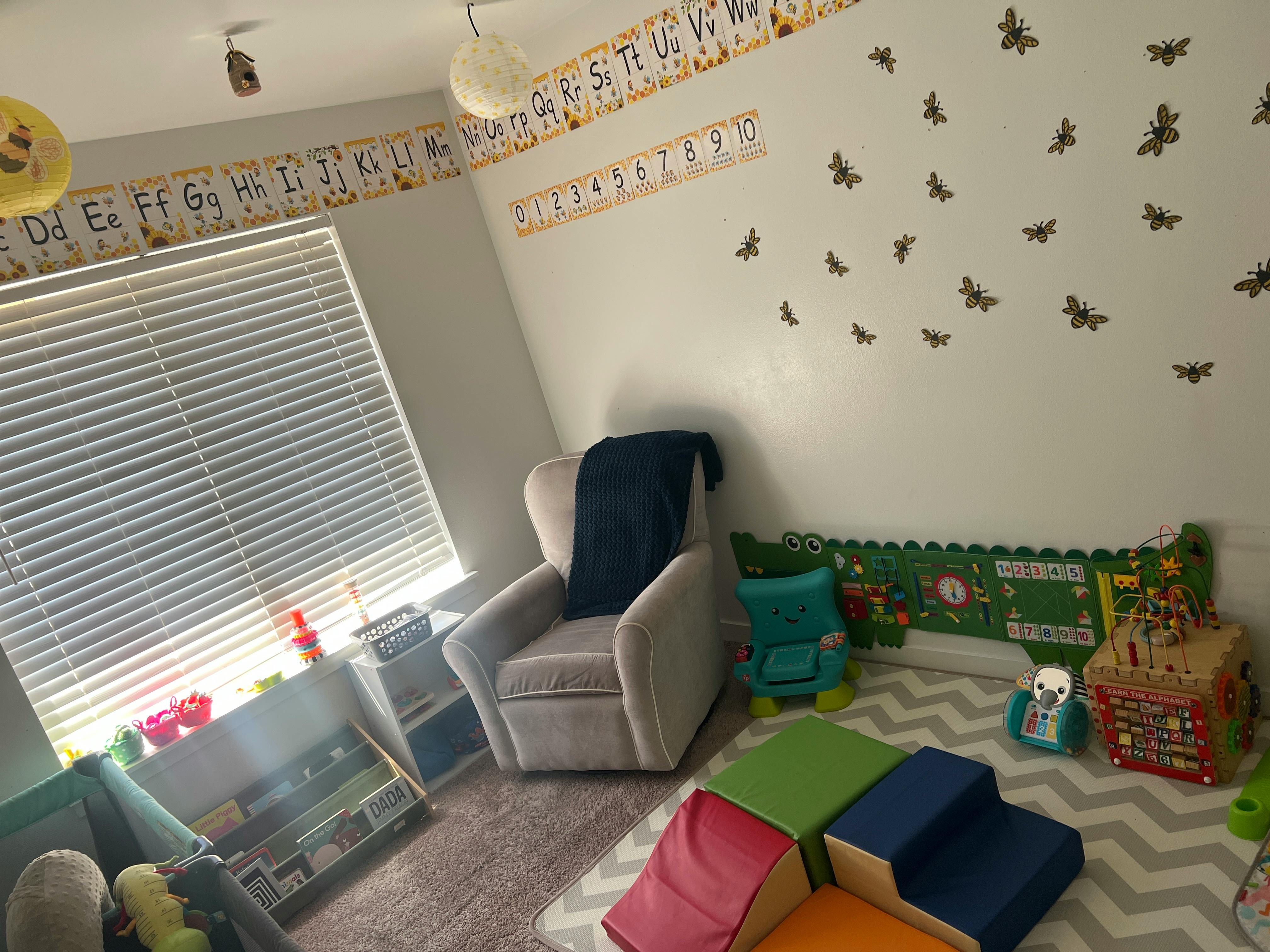 Children's room with alphabet wall decals, a gray chair, and educational toys