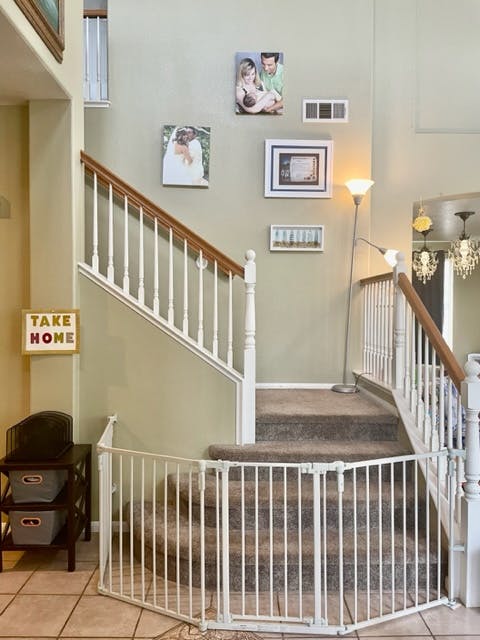 Staircase with a baby gate at the bottom and framed pictures on the wall