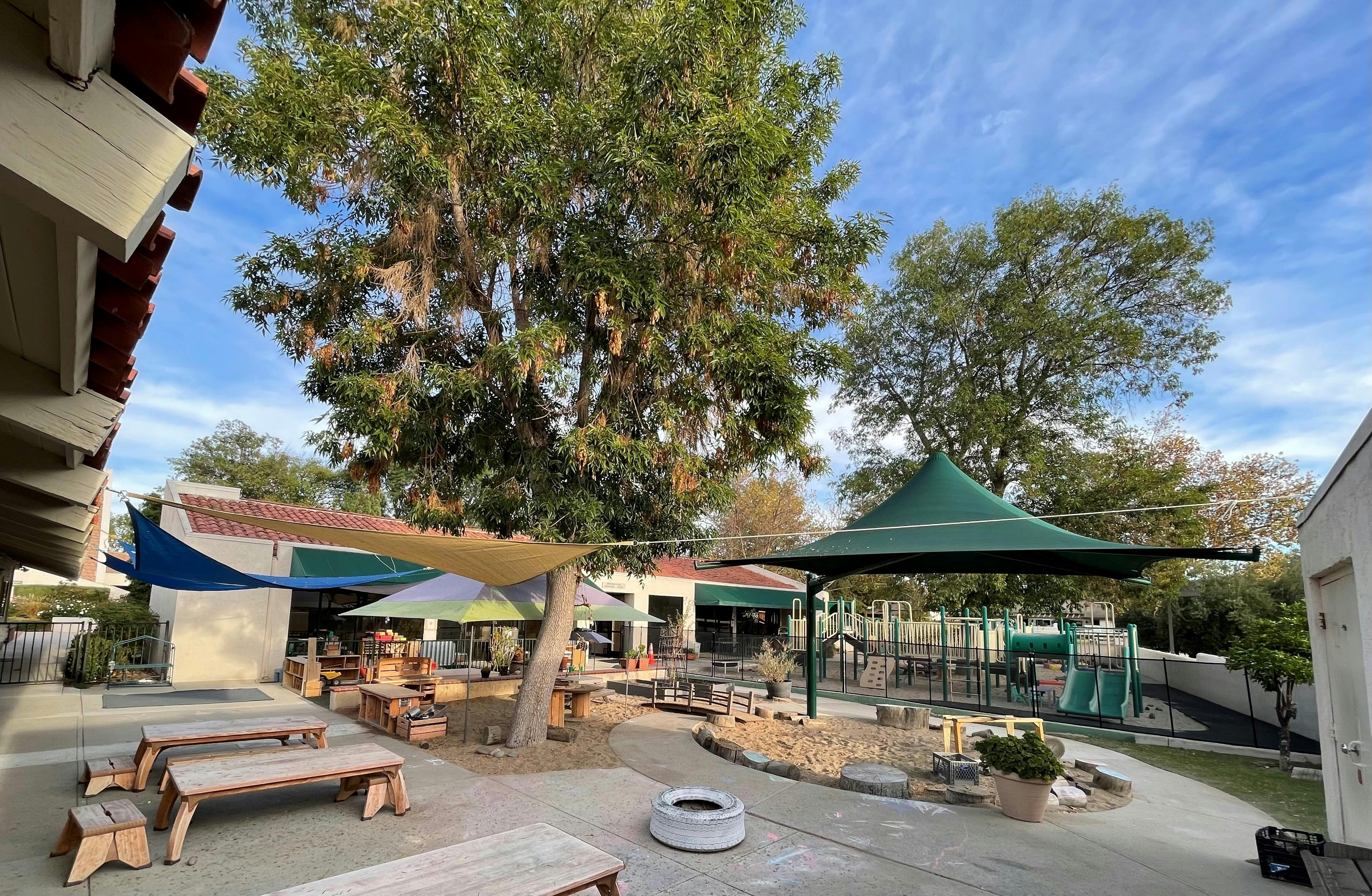 Outdoor playground area with picnic tables and shade structures