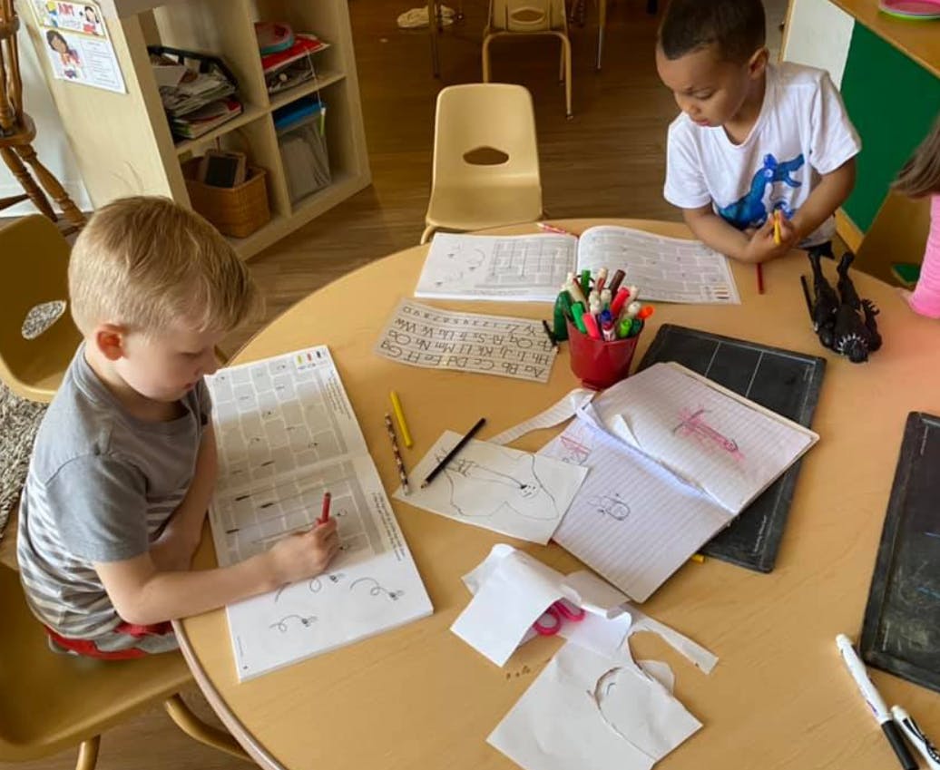 Two children drawing at a table in a classroom