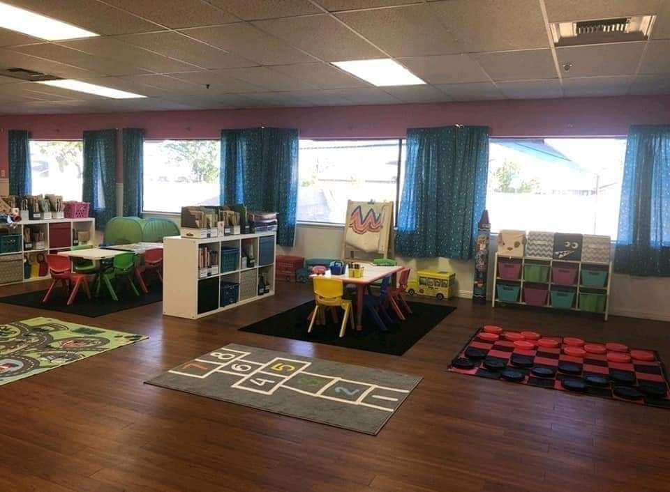 Classroom with small tables and chairs, storage shelves, and rugs